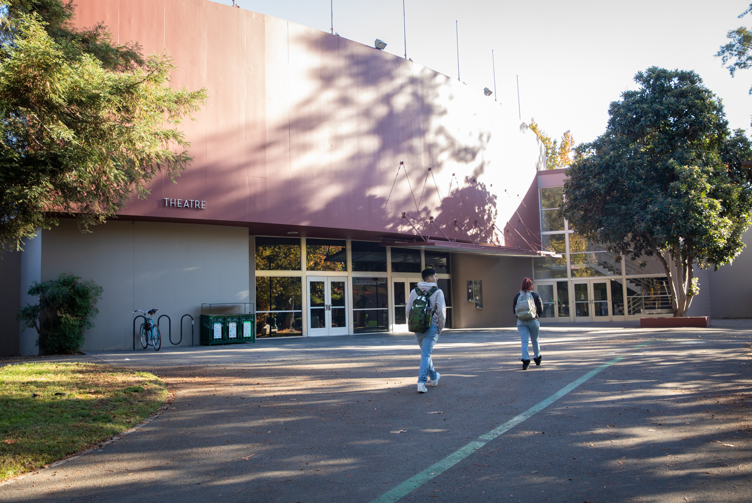 A student walks by Shasta Hall, past the doors to the lobby of the theater