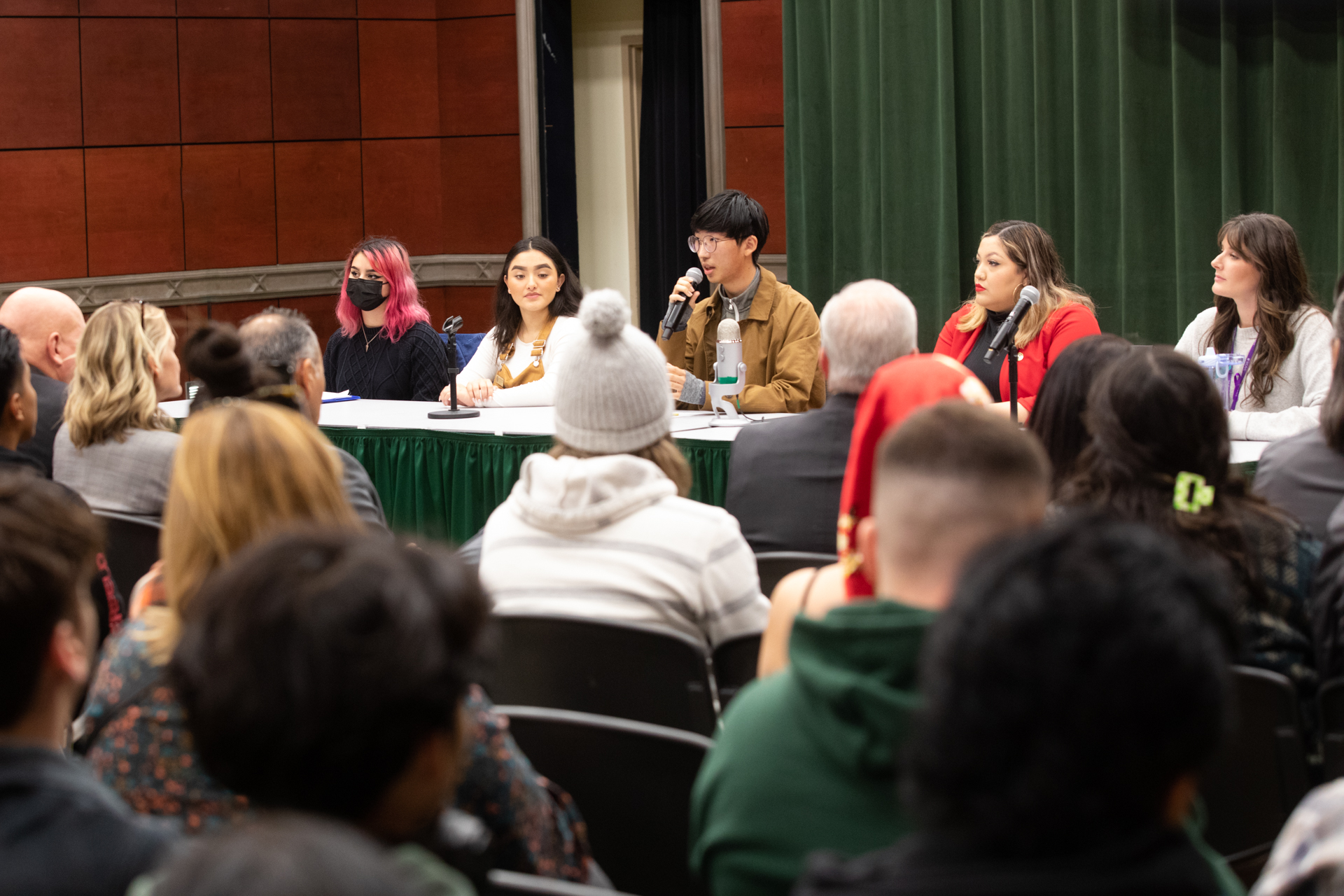 Five individuals sitting at a table, with microphones in front of them, during a campus forum on safety