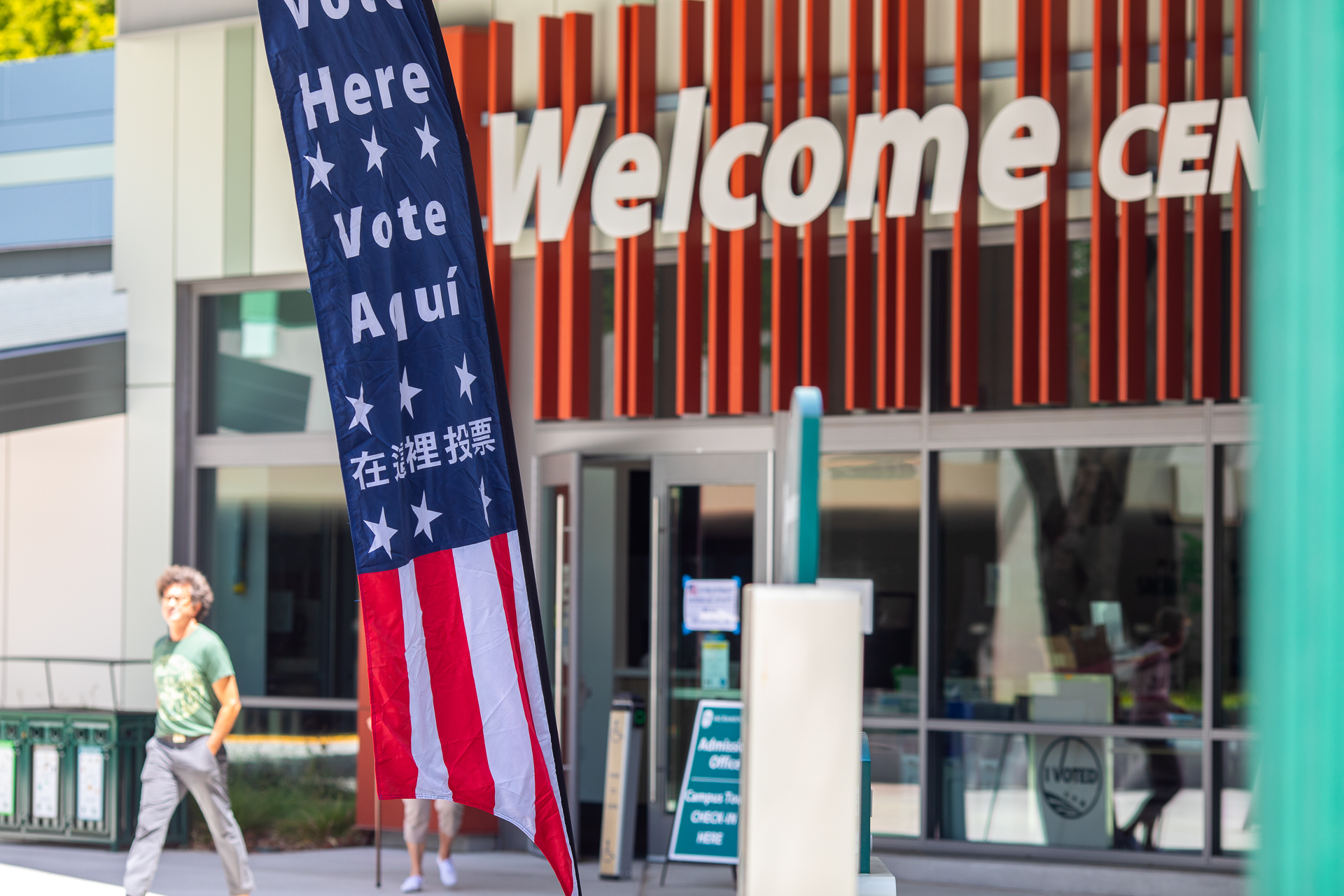 The Sacramento State Welcome Center, with a red, white, and blue flag reading "Vote here" in multiple languages displayed in front.