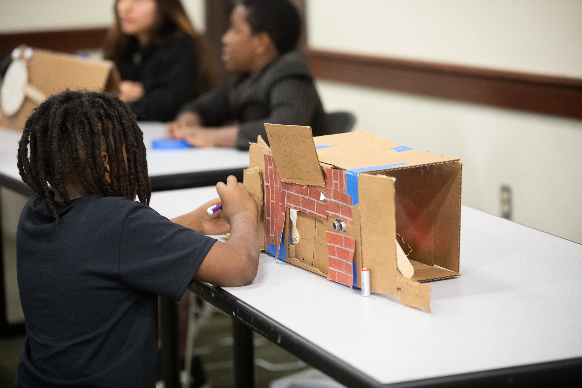 A student works on a cardboard-crafted working gas station model during the Tech Art Summit at Sacramento State.