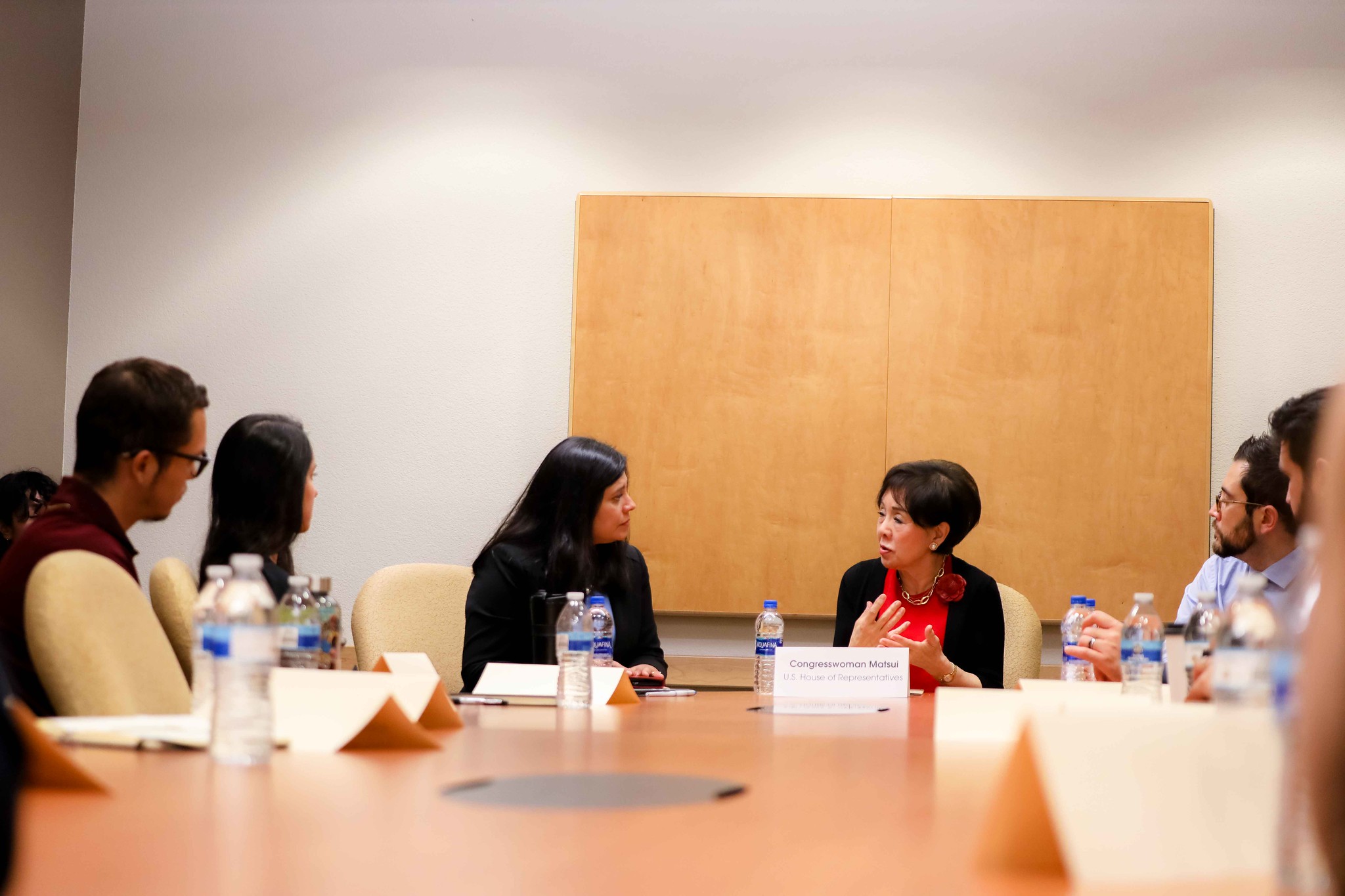 Congresswoman Doris Matsui, indoors sitting at a conference table, talking with other seated individuals