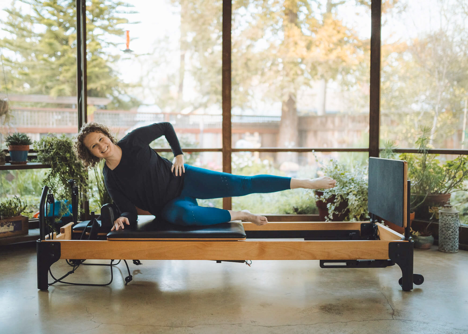Wearing teal and black workout gear, Kaleen Canevari demonstrates a Pilates move on the Flexia exercise machine she brought to the market with help from Sac State’s Carlsen Center for Innovation and Entrepreneurship.