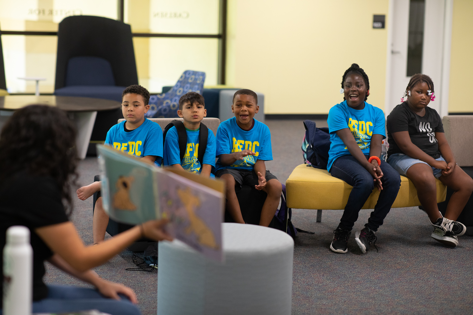 Roberts Family Development Center students wearing blue shirts listen attentively as a story is read from a book during a recent field trip to Sacramento State.