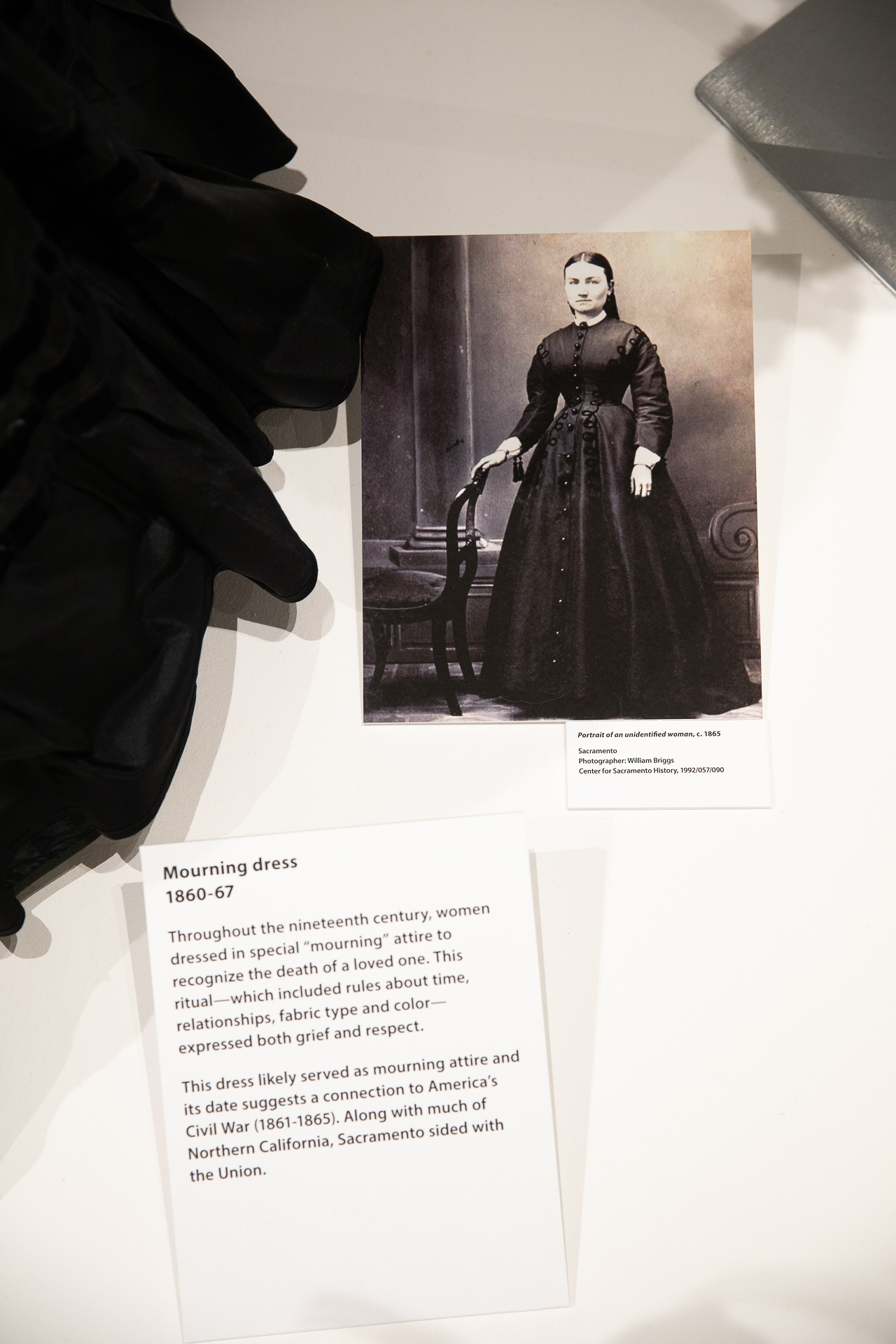 An archival photo and contextual placard are displayed in a showcase as part of the “Dressing Sacramento: 120 Years of Fashion” exhibit, in the Sac State University Library Gallery.