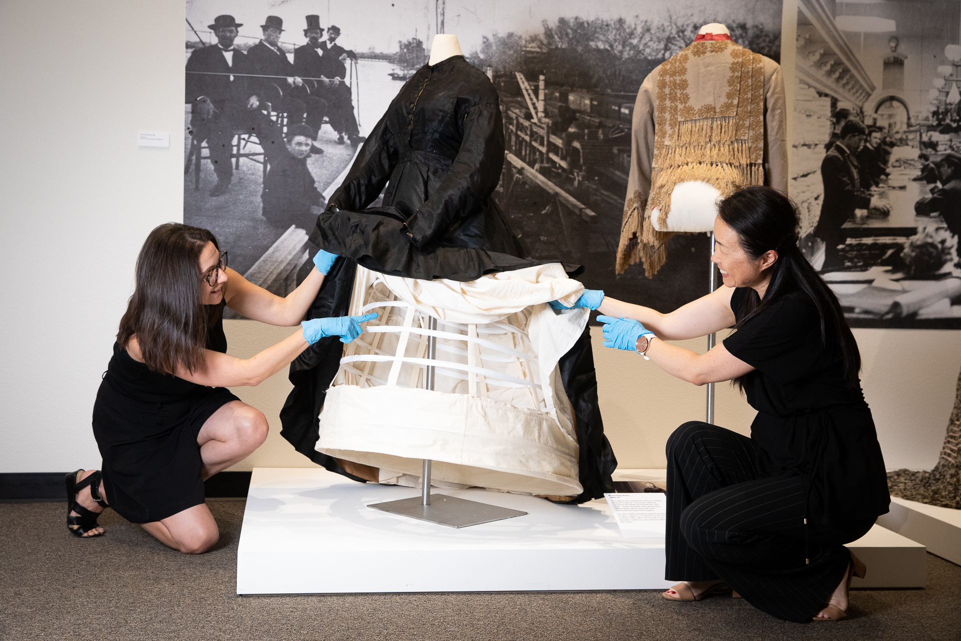 Fashion Merchandising and Management (FASH) Lecturer Taylor Anderson and Dong Shen, FASH program coordinator, set up an 1860s mourning dress on a student-constructed cage crinoline and petticoat display.