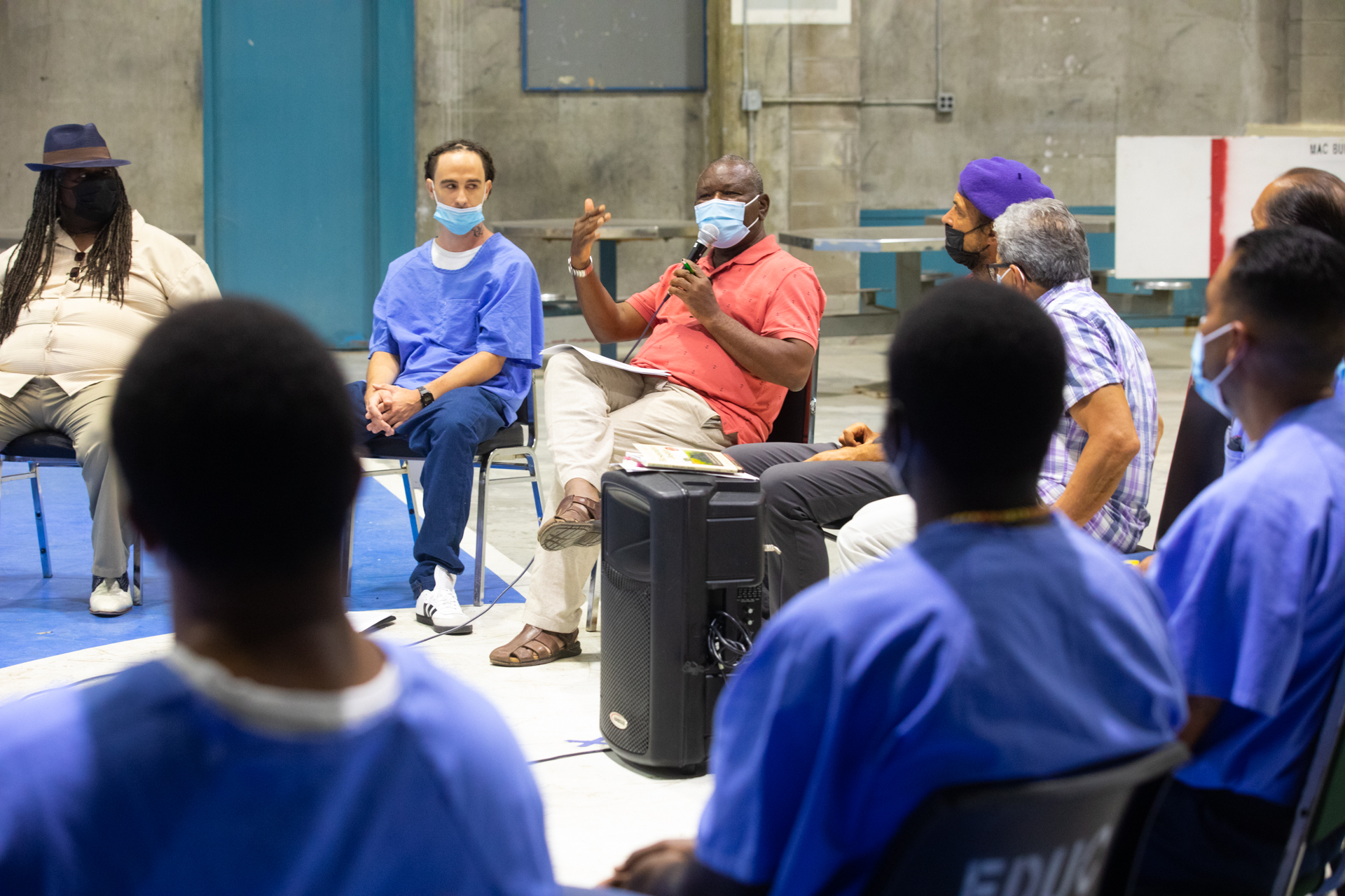 Ernest Uwazie, Sac State Division of Criminal Justice chair, sits in a circle of inmates and restorative justice participants wearing an orange shirt as he addresses the group during a workshop.