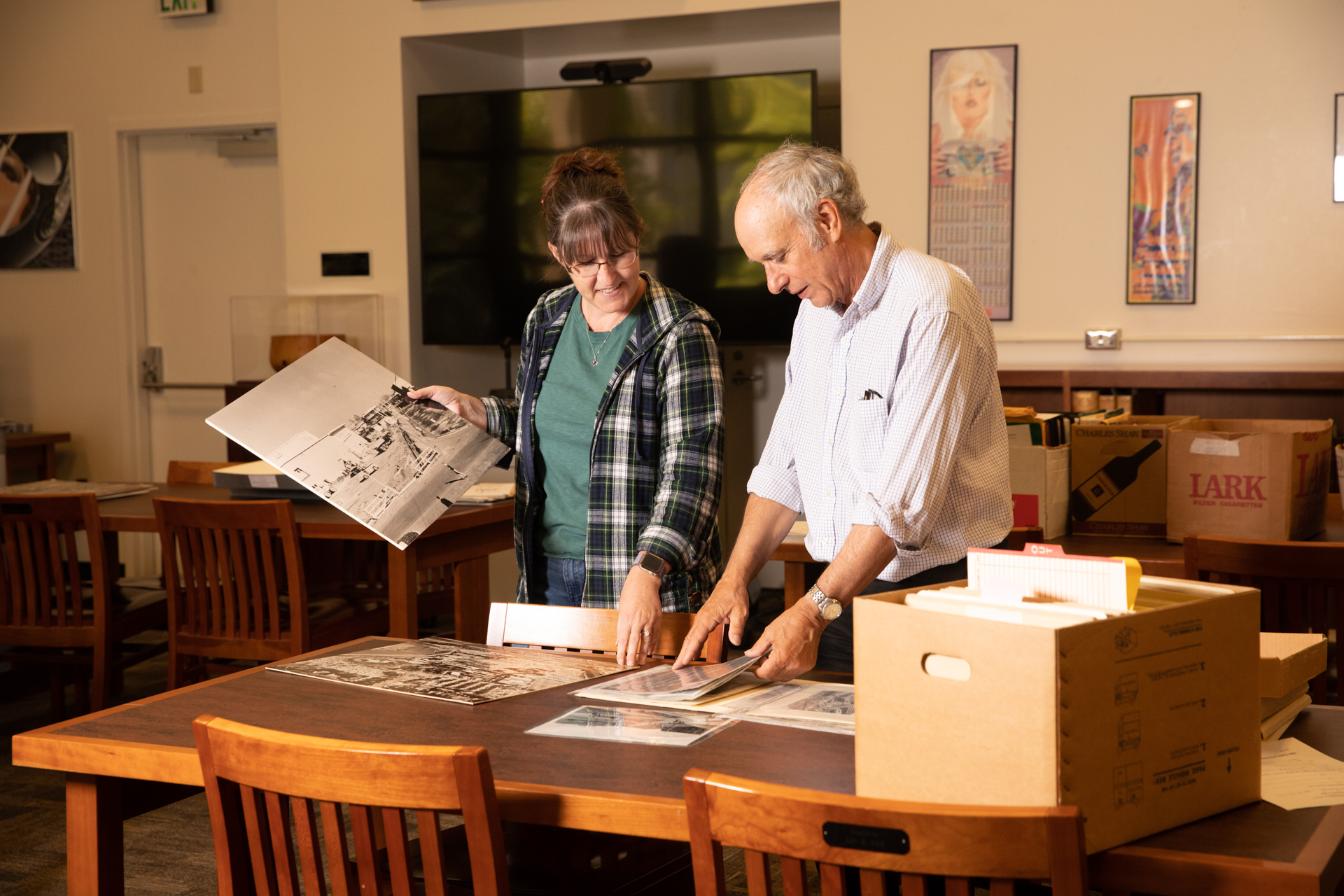 University Library Archives staff rummage through boxes of historical images of the University to find items for a 75th Anniversary exhibit.
