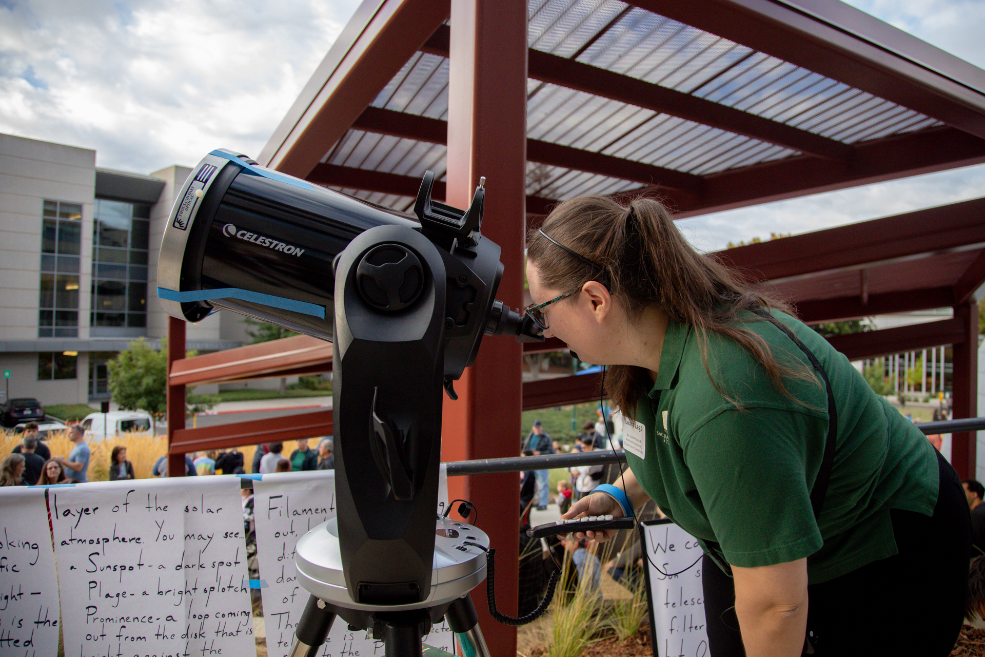 A woman views the solar eclipse through a telescope.
