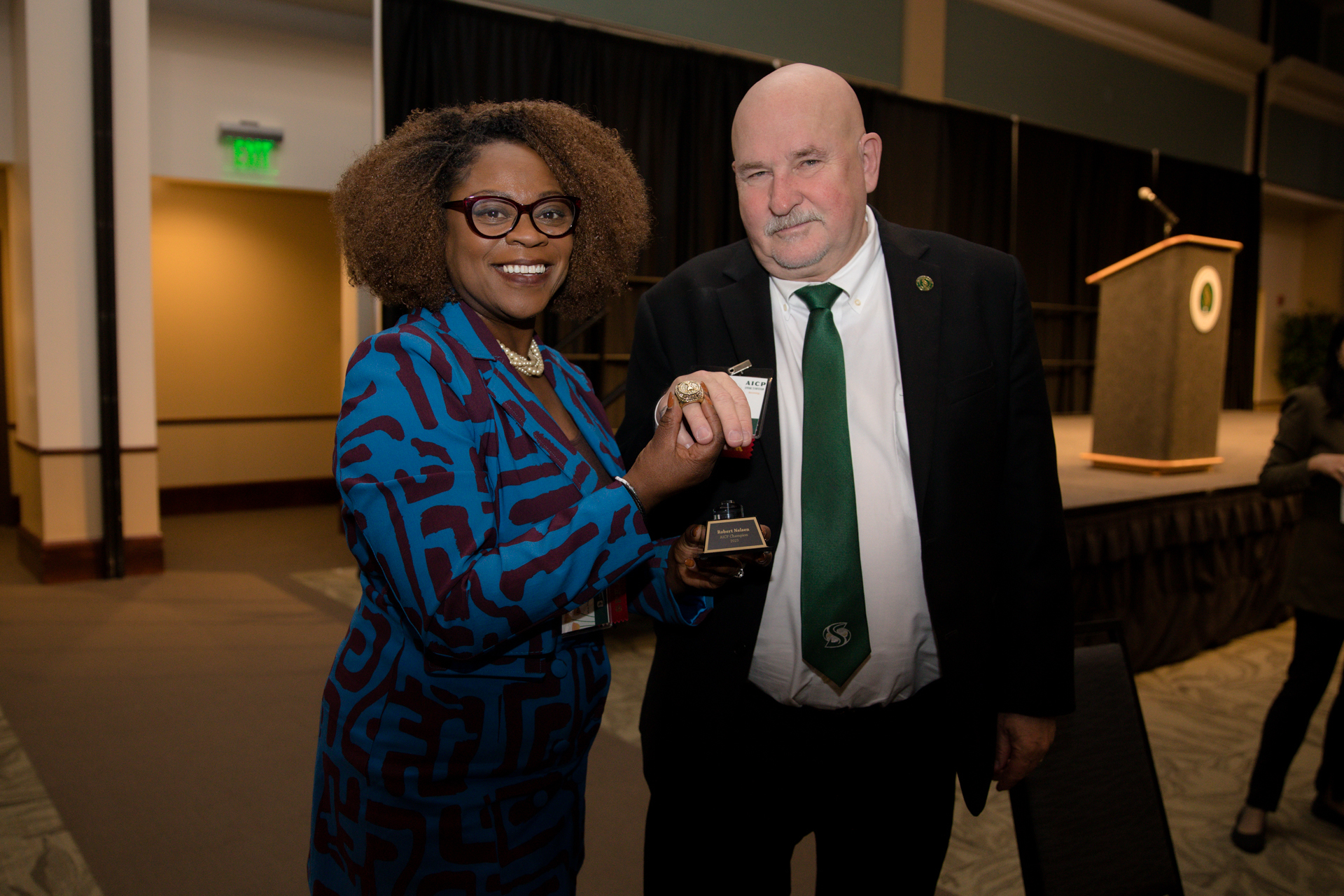 President Robert S. Nelson and Mia Settles-Tidwell posing with Nelsen's AICP championship ring.
