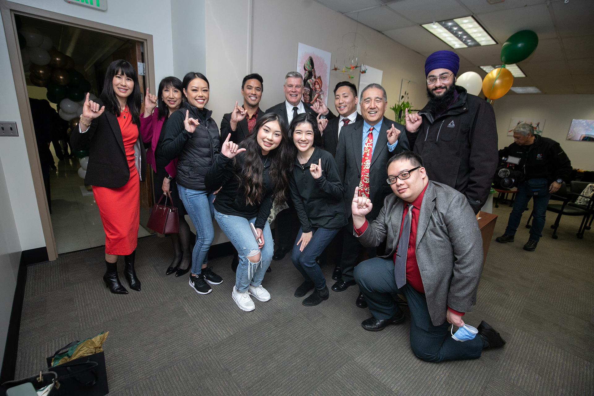 Students and other Sac State campus community members salute "Stingers Up" with a pinky in the air at the APIDA Center.