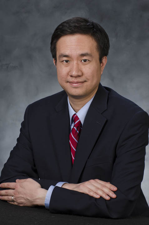A portrait of Eric Lin in a suit and tie.