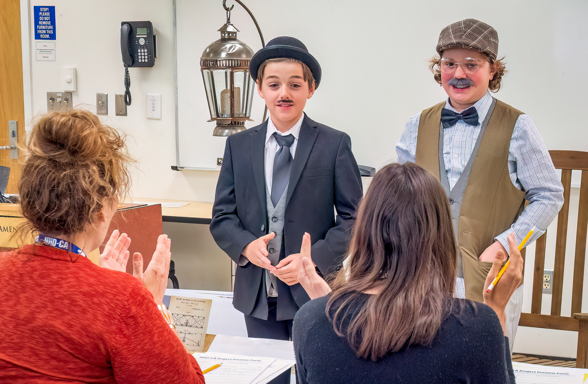 Two boys dressed in costumes portraying historical figures present their project to judges.