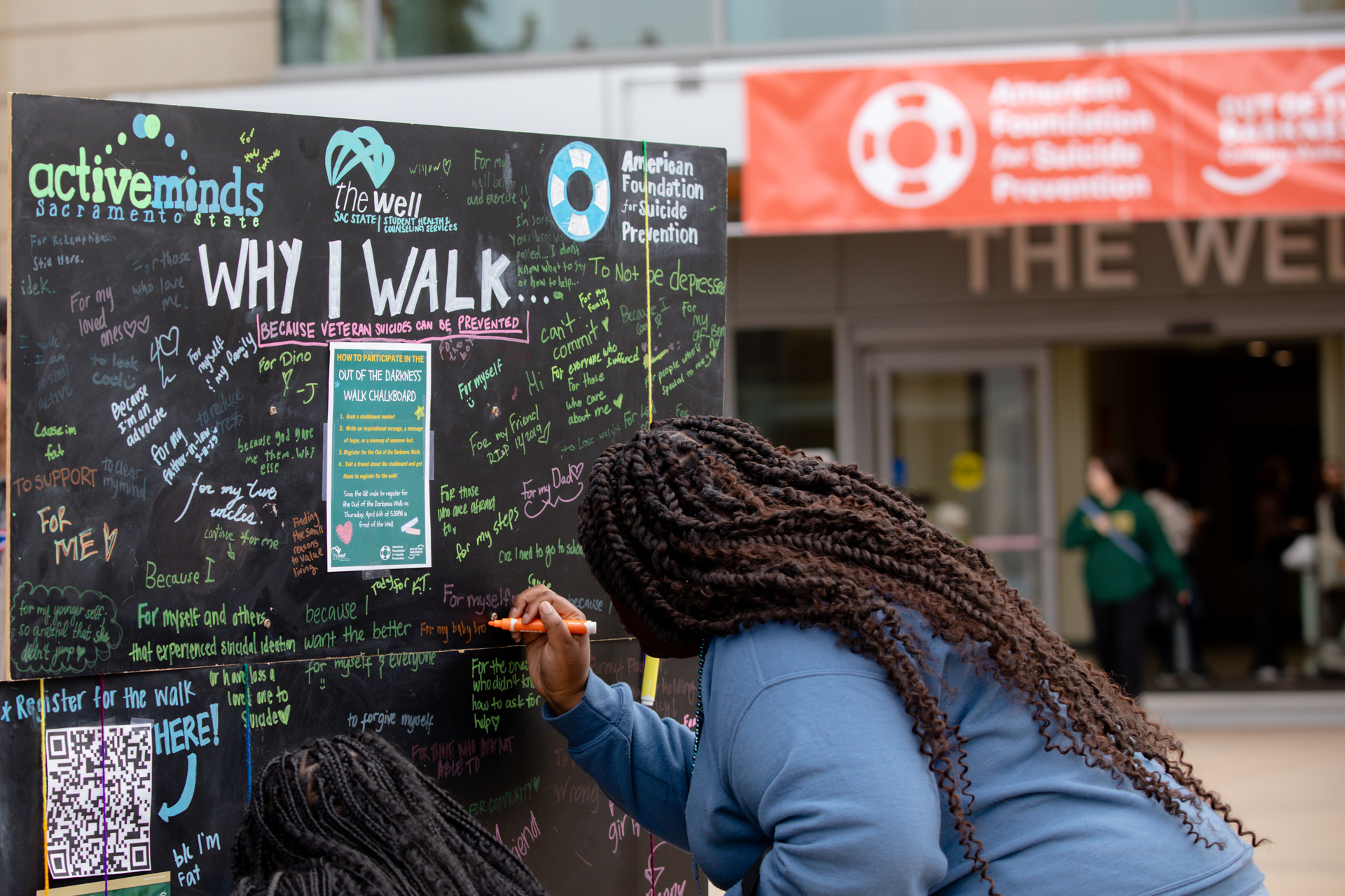 A member of the Sac State campus community writes words of encouragement on a chalk board. 