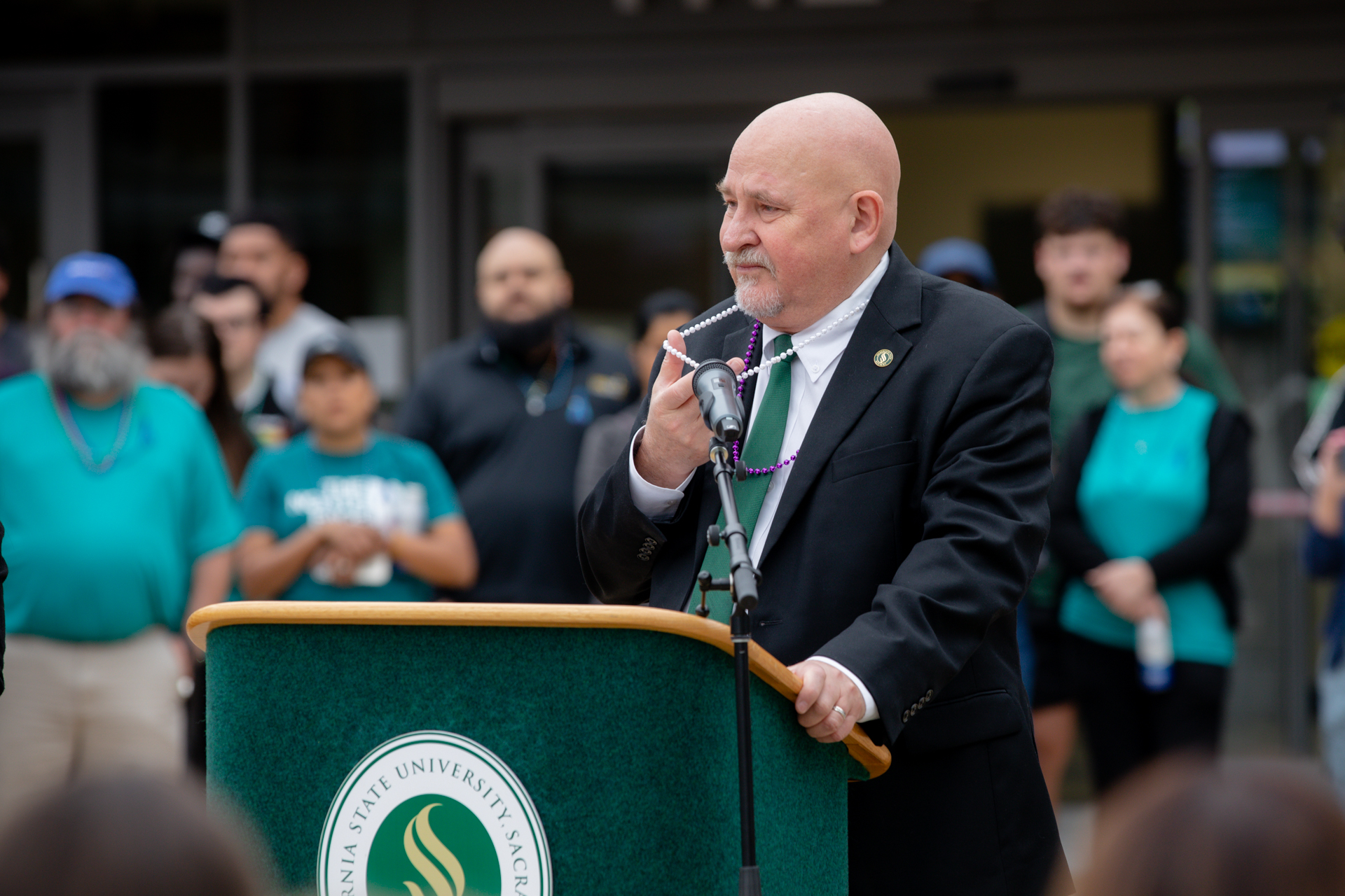 Sacramento State President Nelsen speaks about suicide prevention while wearing purple and white beads.