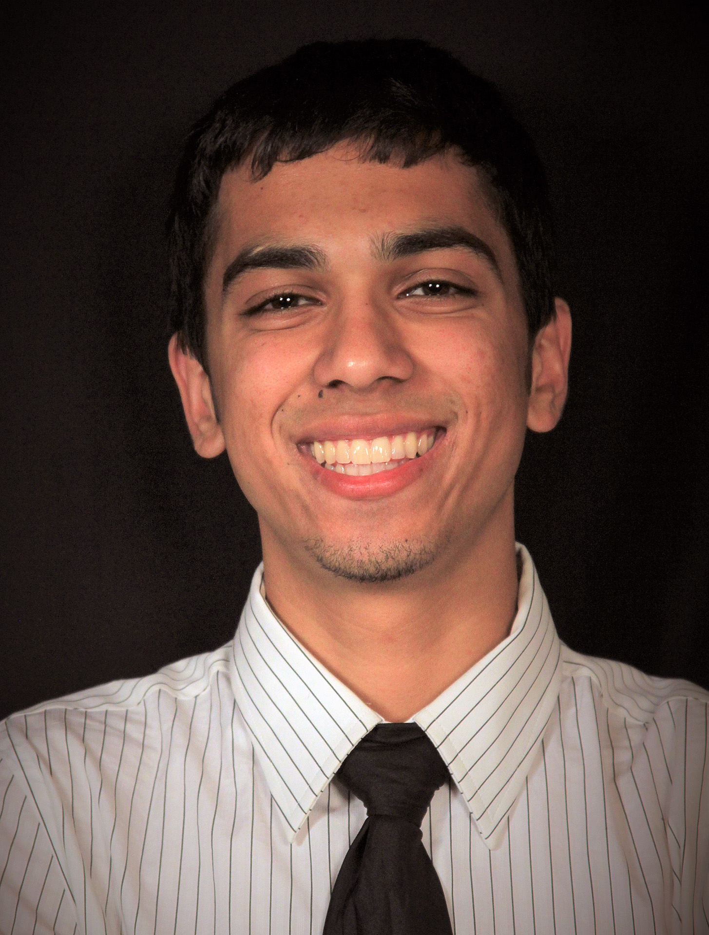 A portrait of Aaron Rehman on a black backdrop.