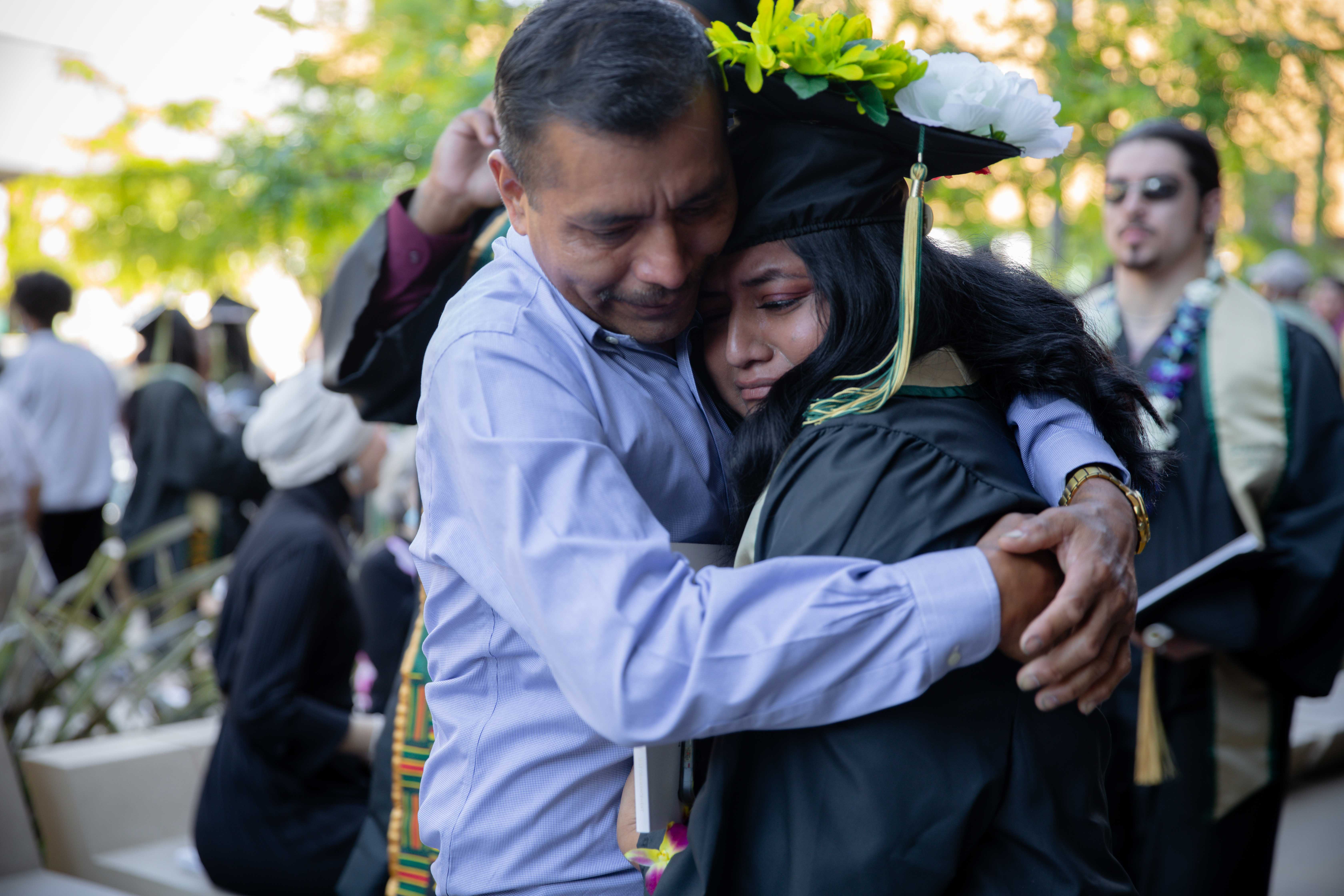 A Sacramento State graduate hugging a man, outside Golden 1 Center