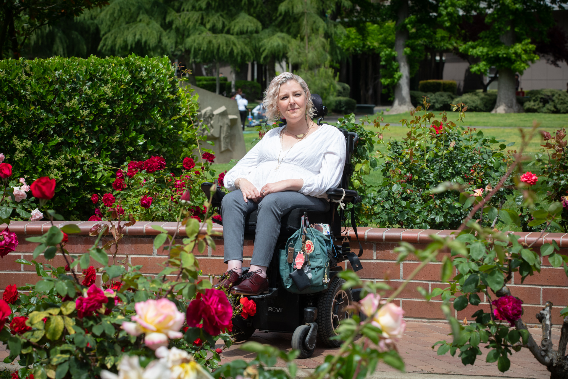 Ed.D. student Rachel Stewart, who has used a wheelchair since the age of 5, enjoys the flowers on the Sac State campus.