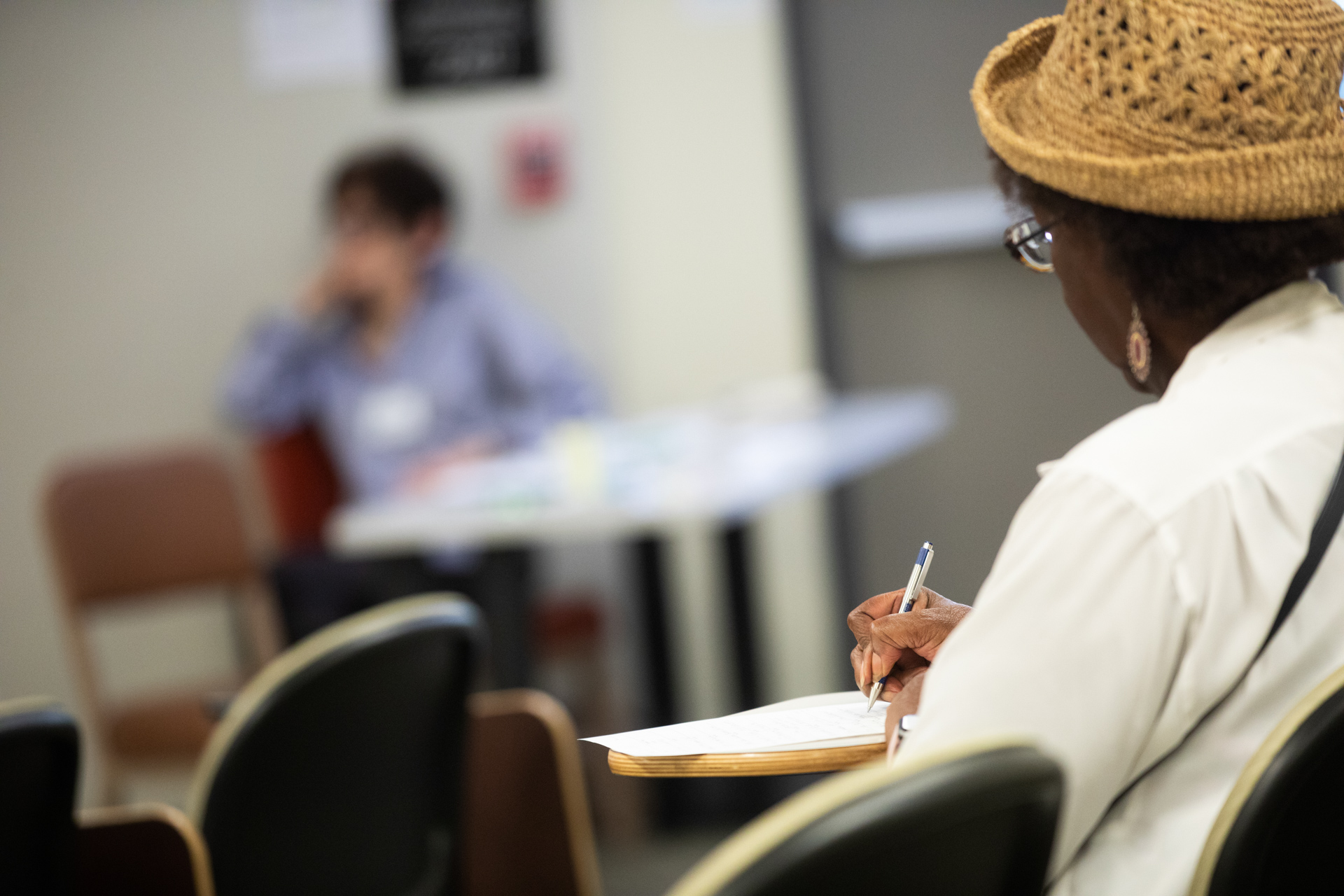 A woman takes notes in class. 