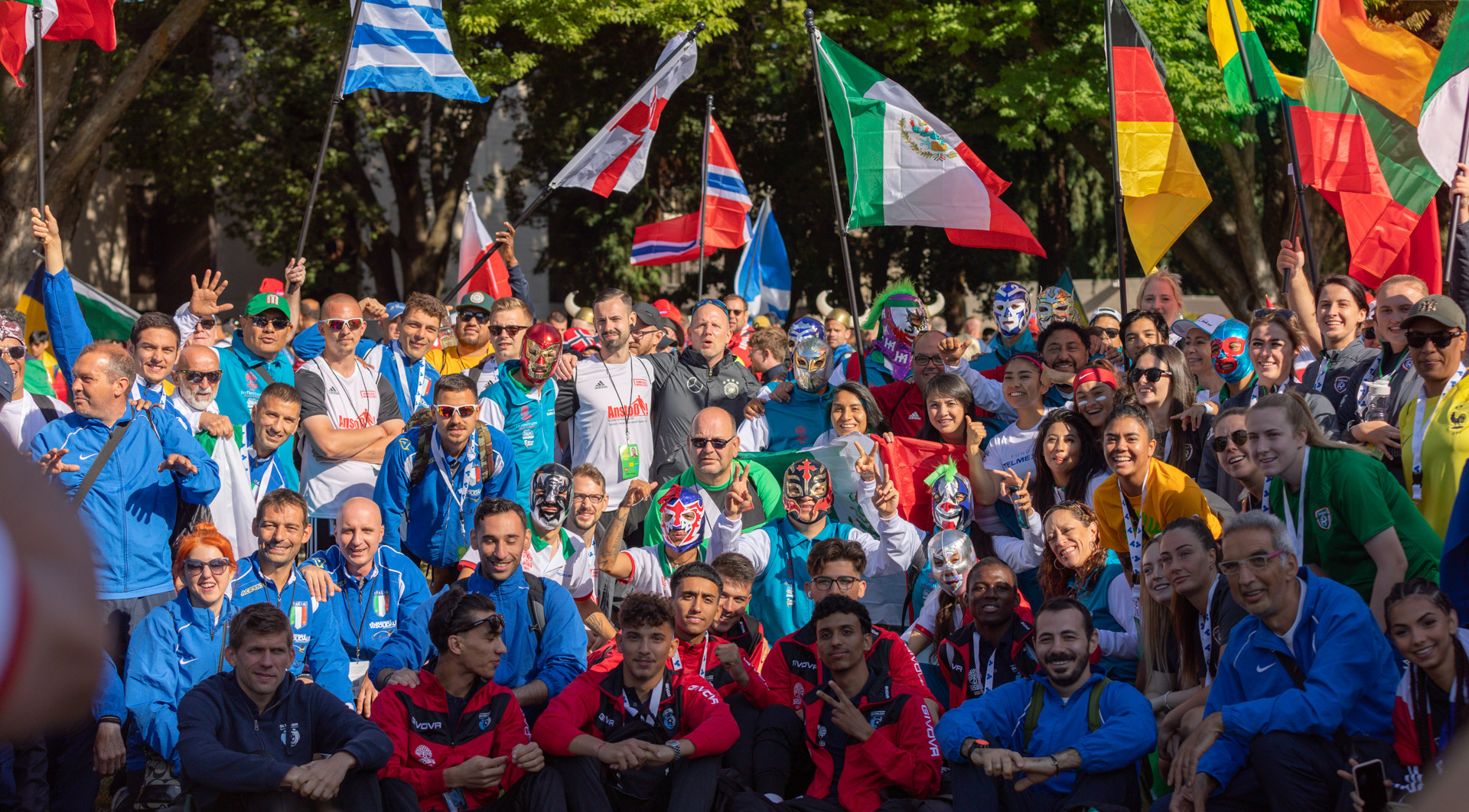 Homeless World Cup participants, coaches and others pose with flags and items representing their countries.