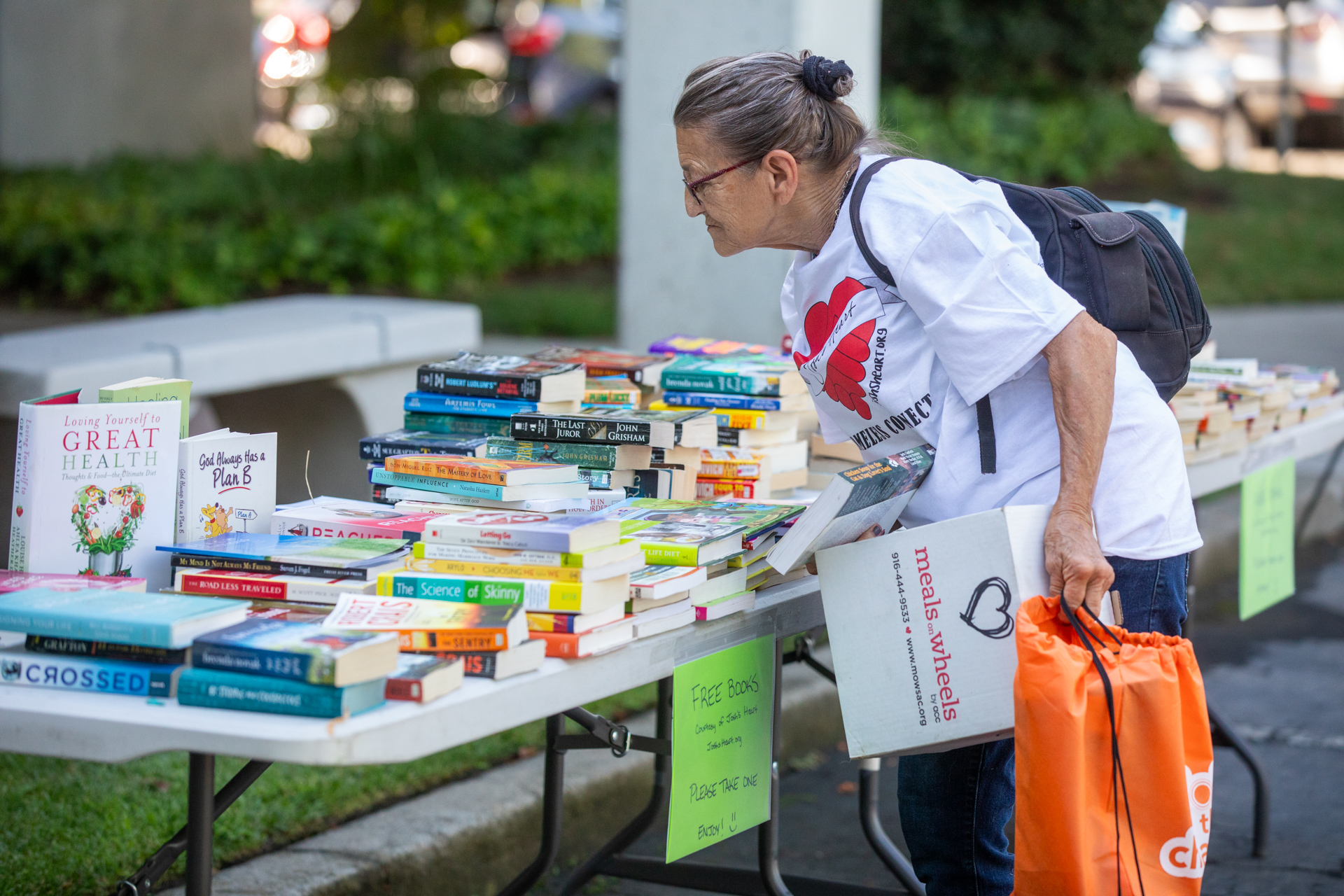 A woman looks at a table full of books.