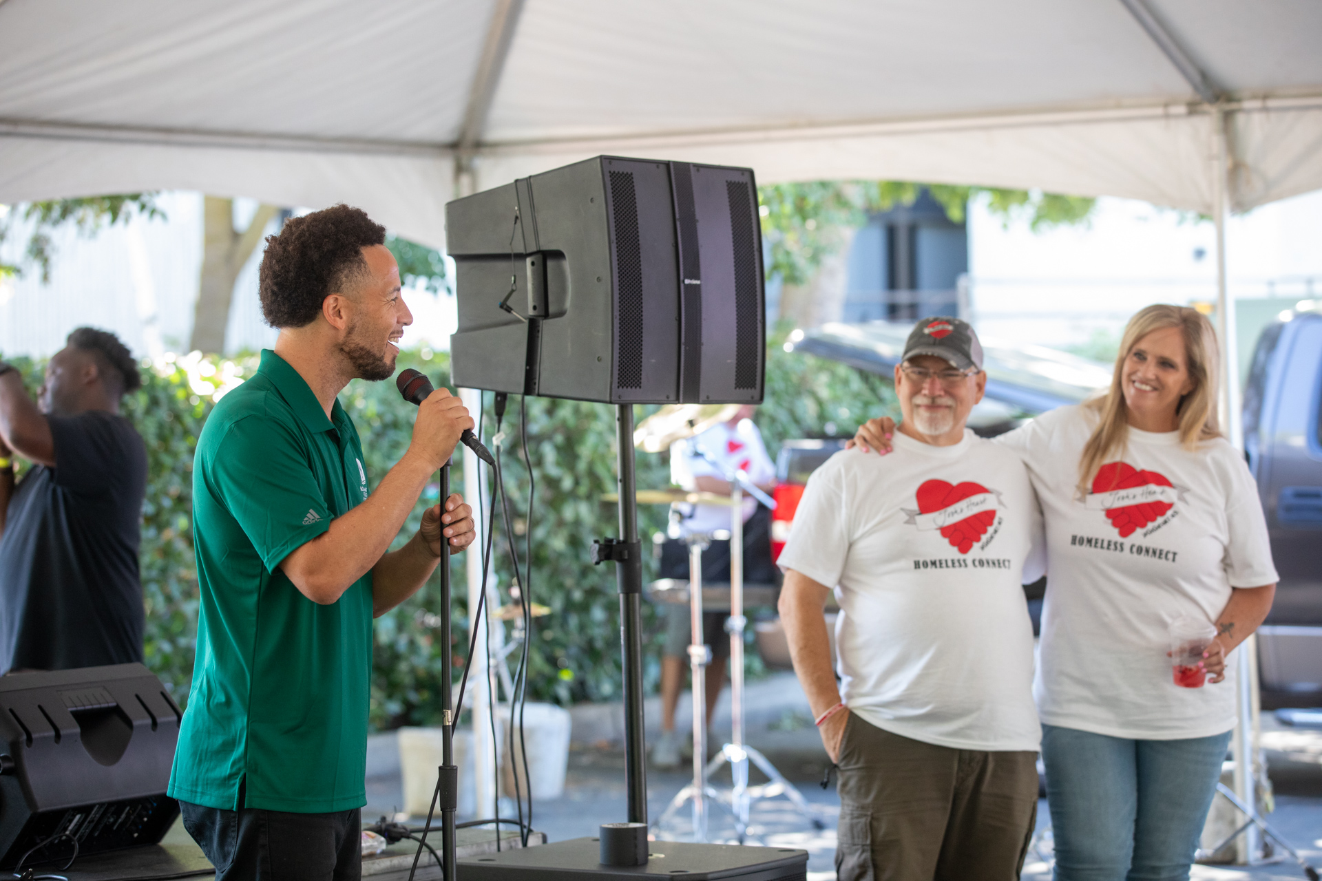 Sac State President Luke Wood speaking into a microphone as Josh's Heart founders Don and Dawn Nahhas look on.