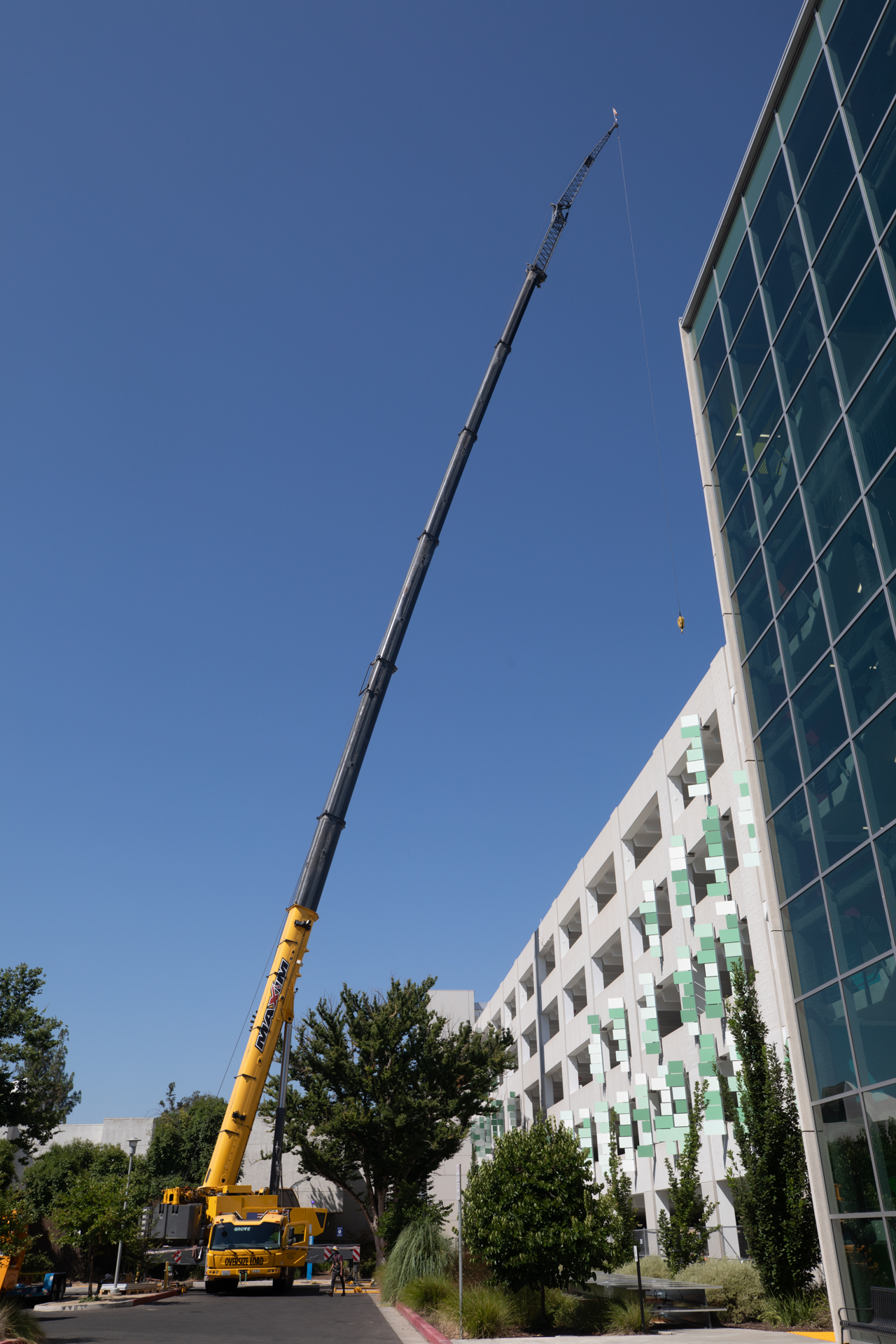 A large crane hoists solar panels to the top of Parking Structure 5 at Sacramento State.