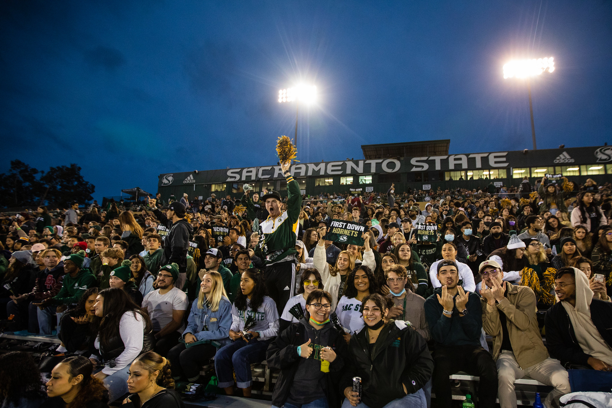 A large crowd fills the stands at Hornet Stadium during a night football game.