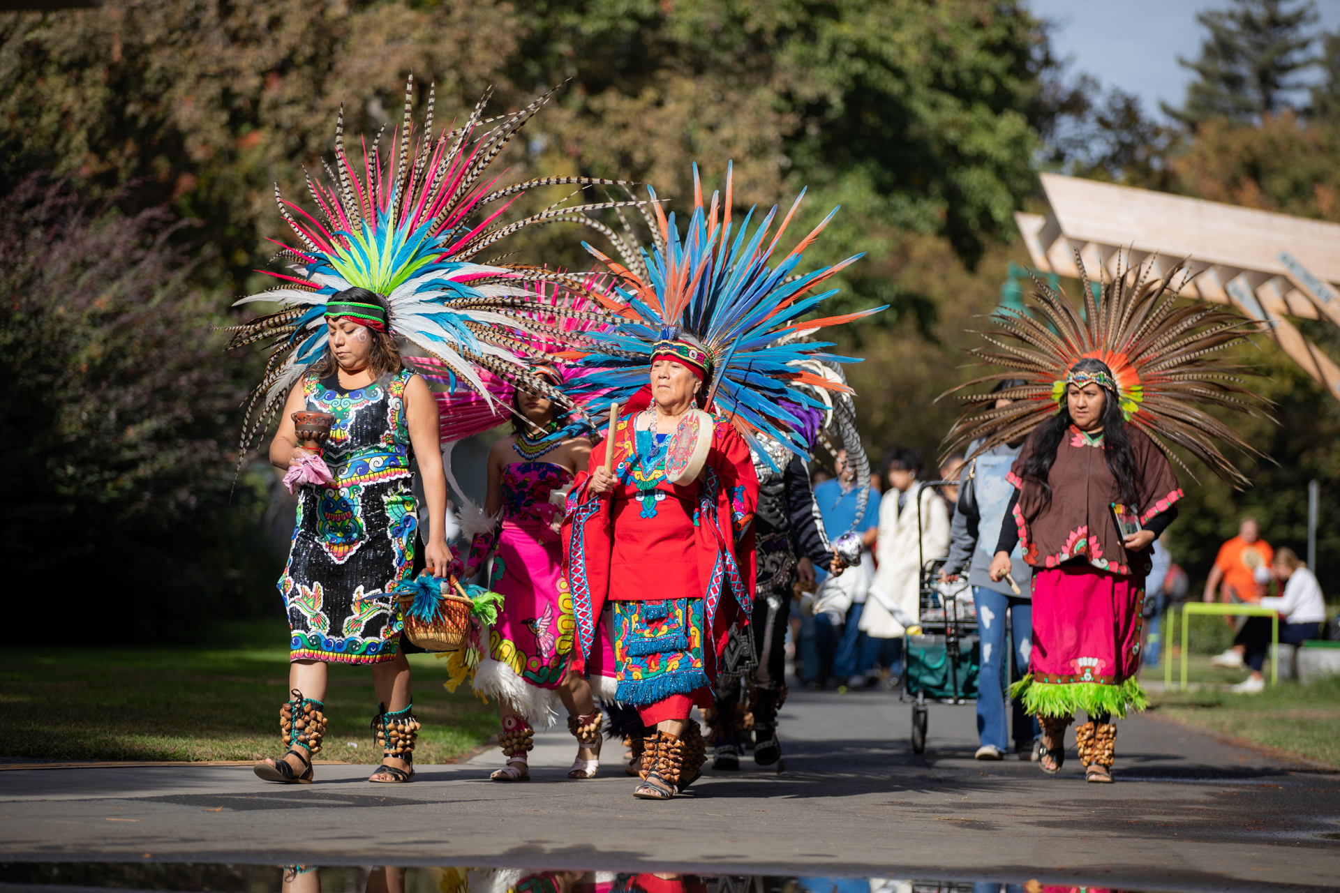 Women in traditional Mexican clothing lead a Dia de los Muertos parade through campus.