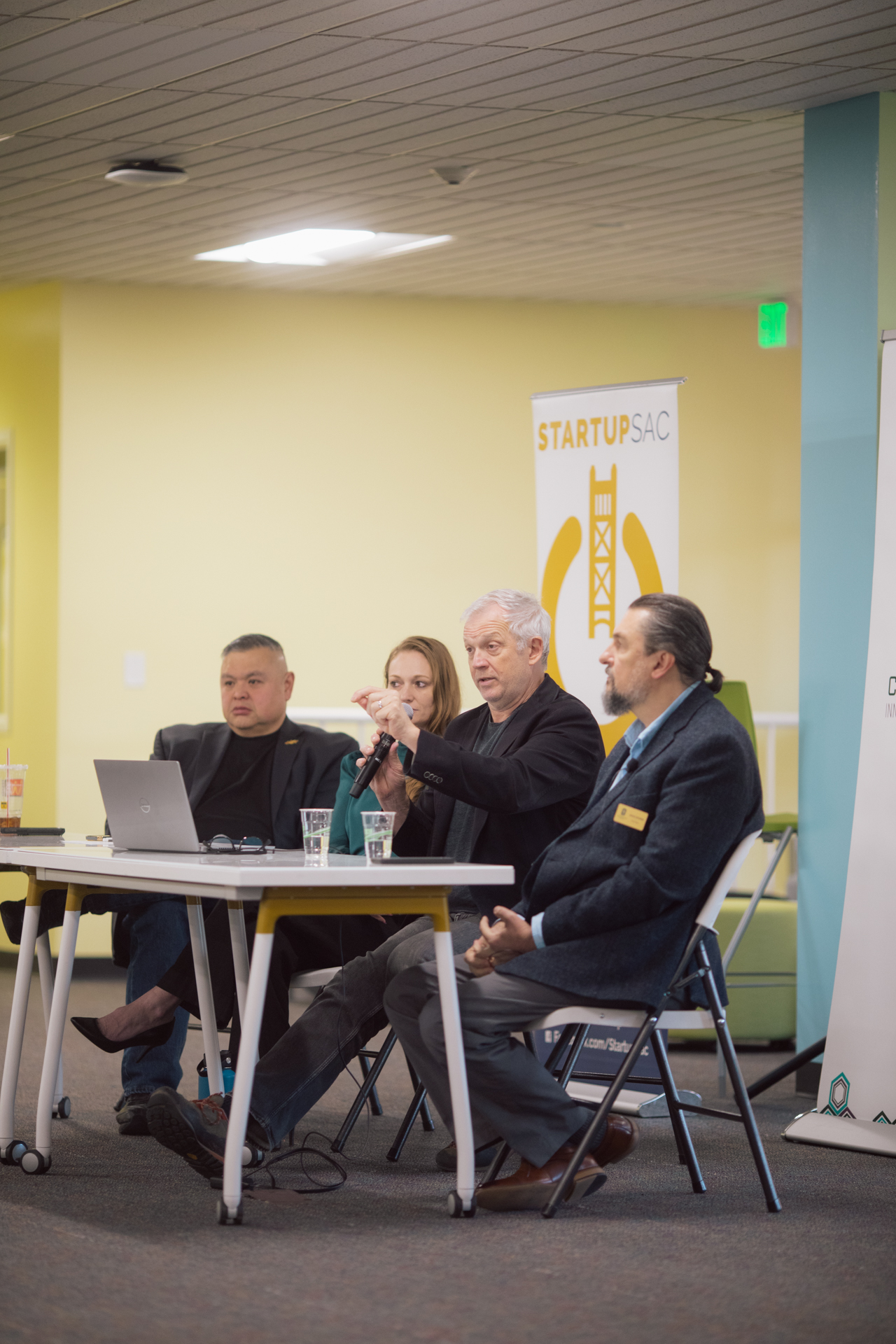 Four individuals seated at a table during a panel discussion at the Carlsen Center.