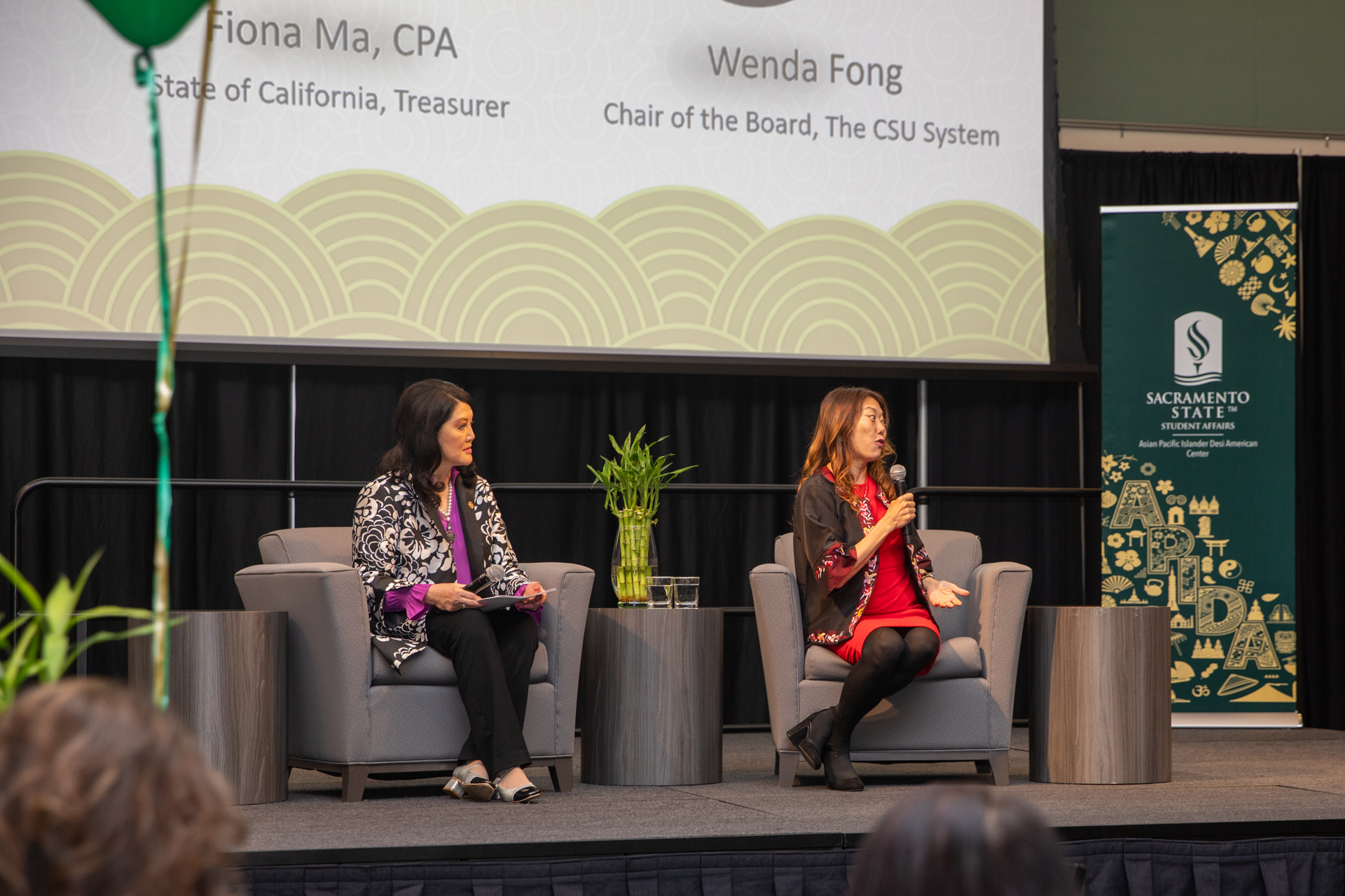 CSU Trustee Wenda Fong and State Treasurer Fiona Ma sitting on a stage, speaking to APIDA College Day attendees.