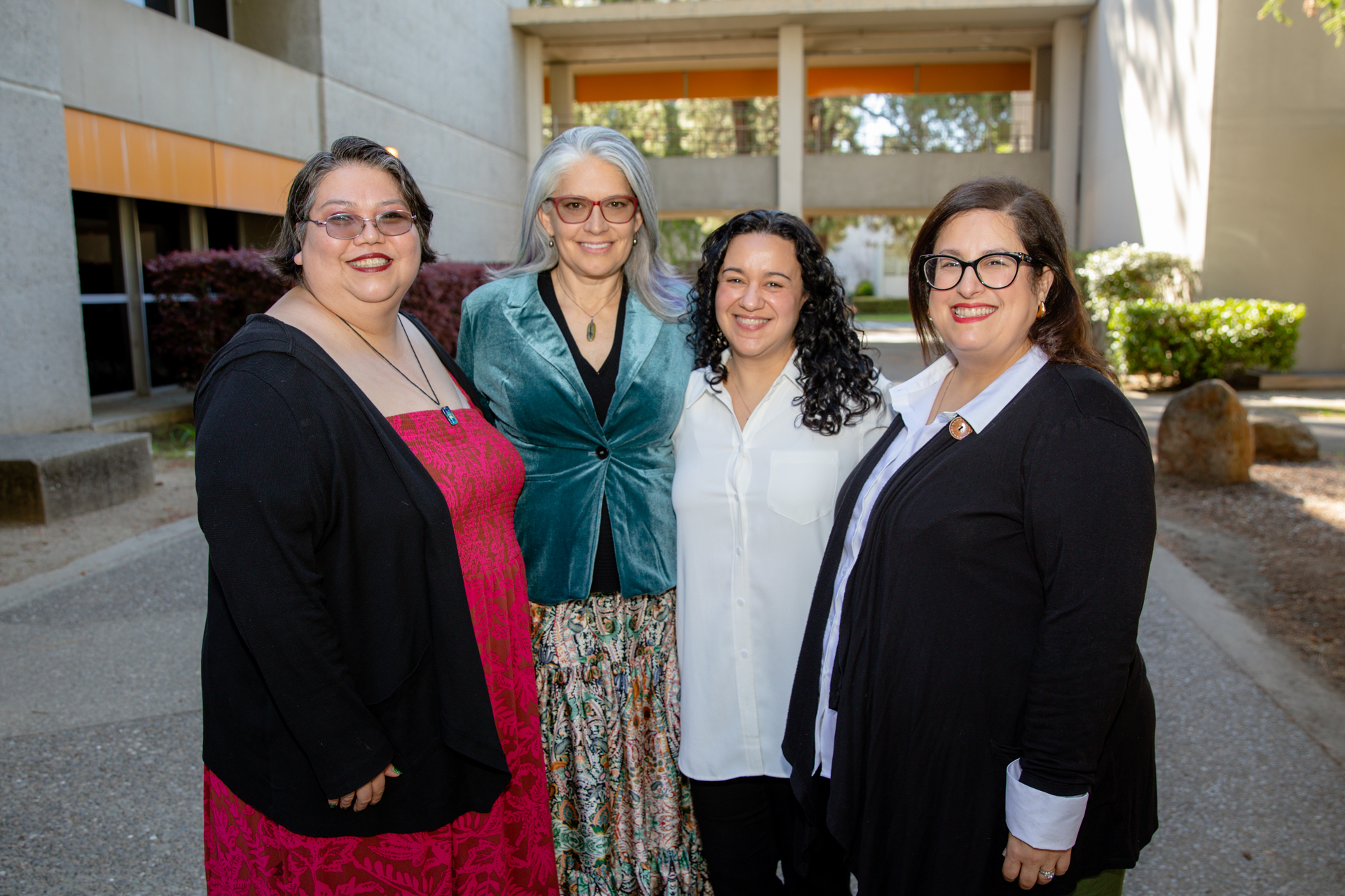 Four Sac State faculty pose for a photo outdoors.