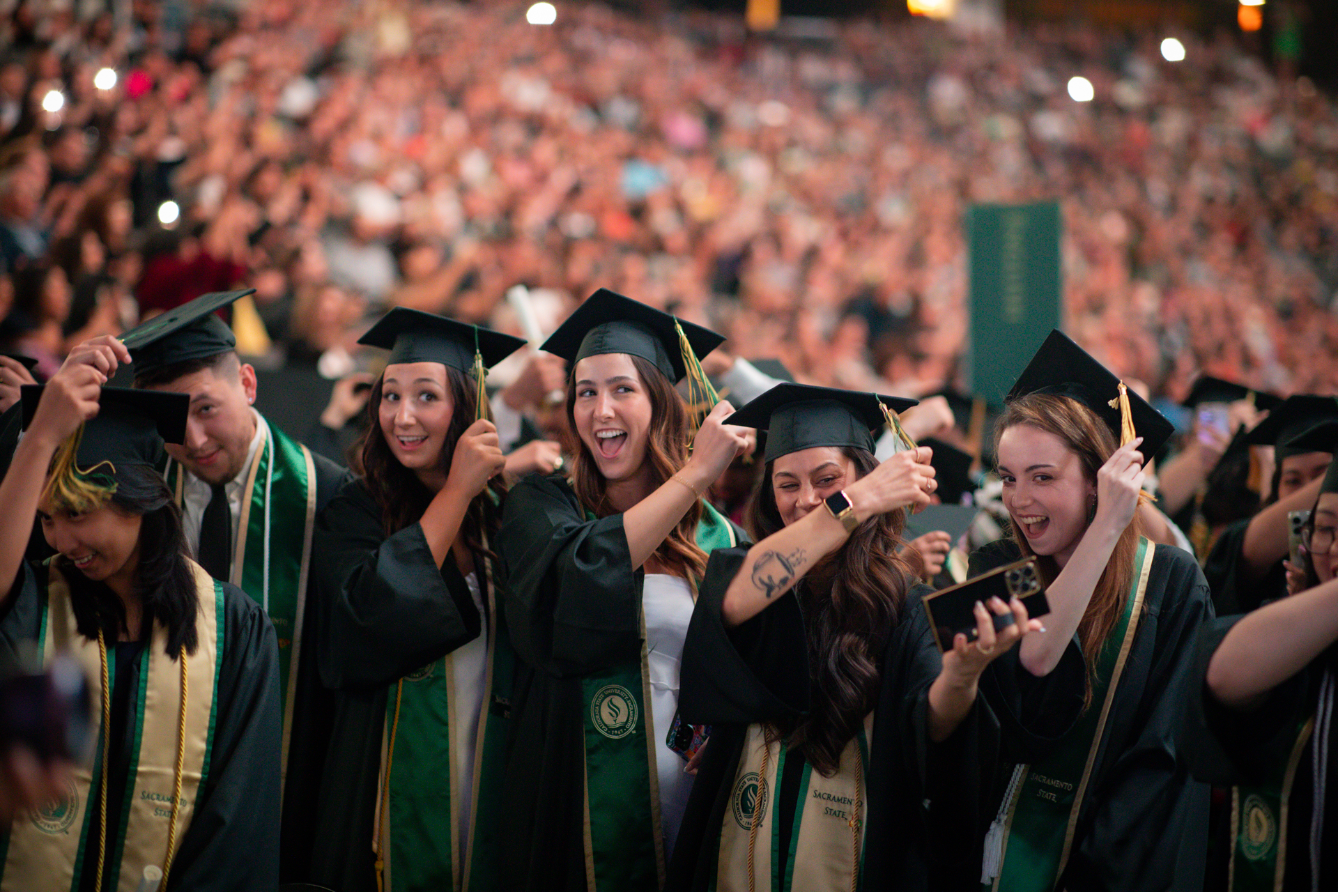 A group of Sac State graduates moving the tassels on their mortar boards.