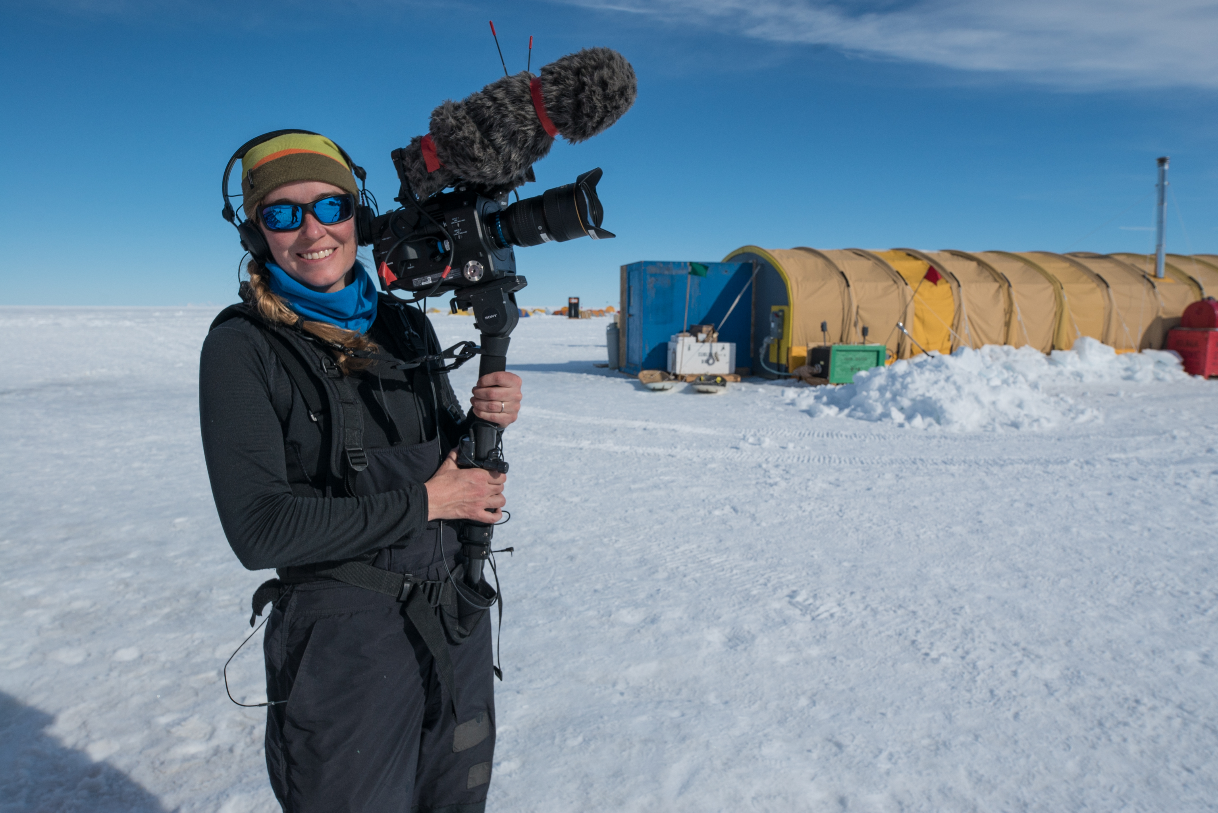 Kathy Kasic, outside in Antarctica, holding a camera.