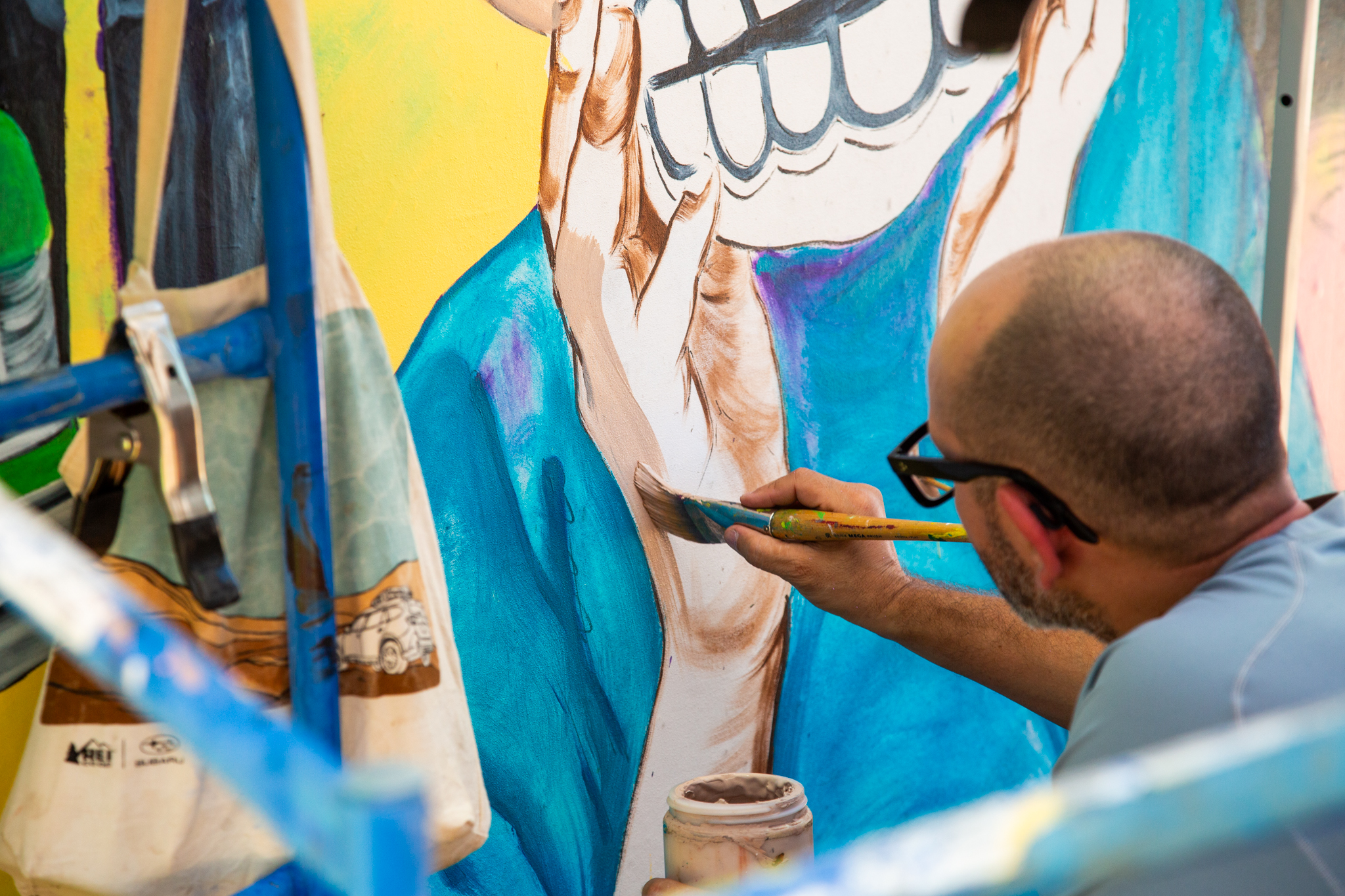 An artist paints on a wall that will be part of A Place of Belonging mural.