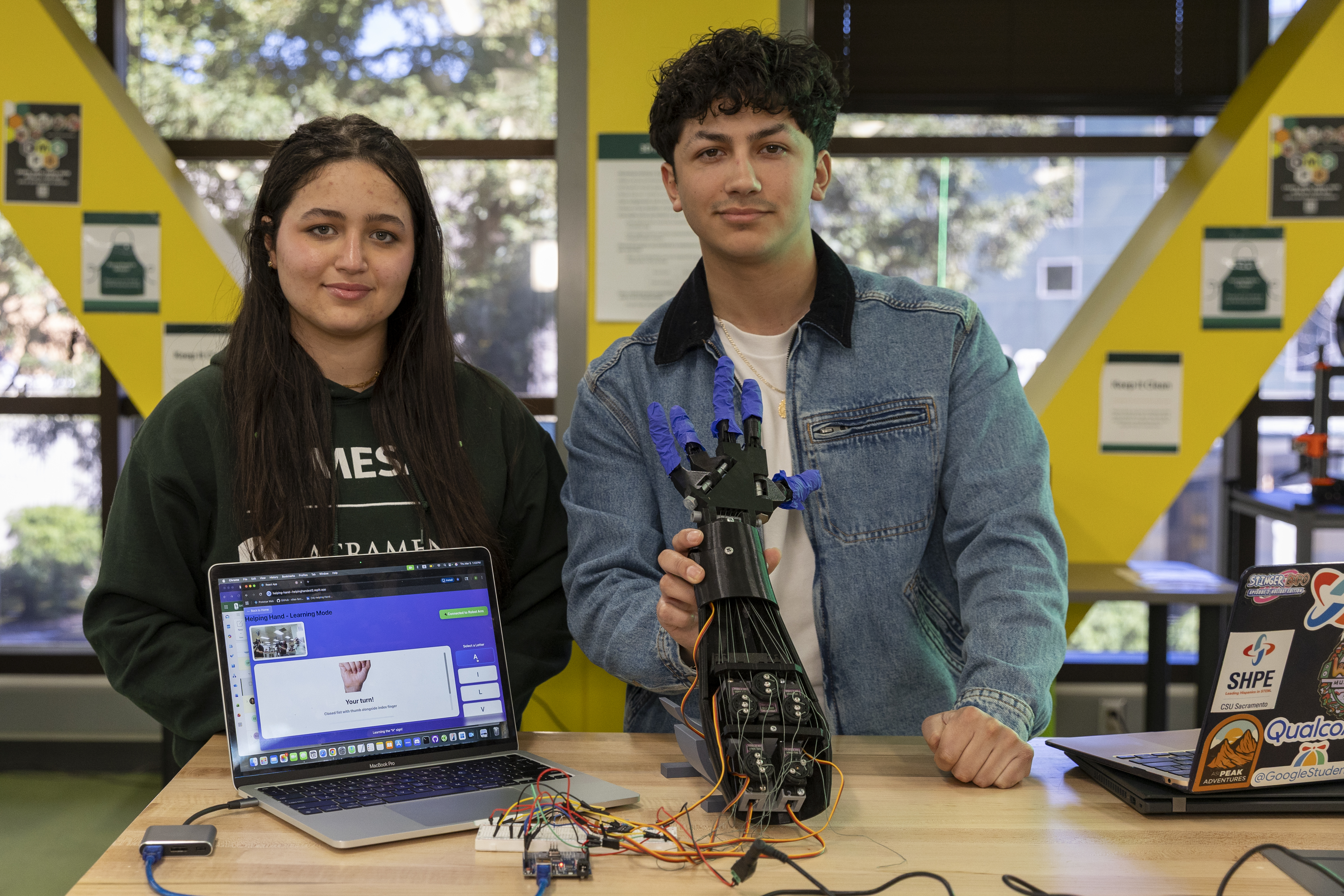 Helping Hand co-founders Salma Waleed Aboukhadra and Edgar Sanchez demonstrate the robotic arm they built to teach American Sign Language. (Sacramento State/Analy Carrillo)