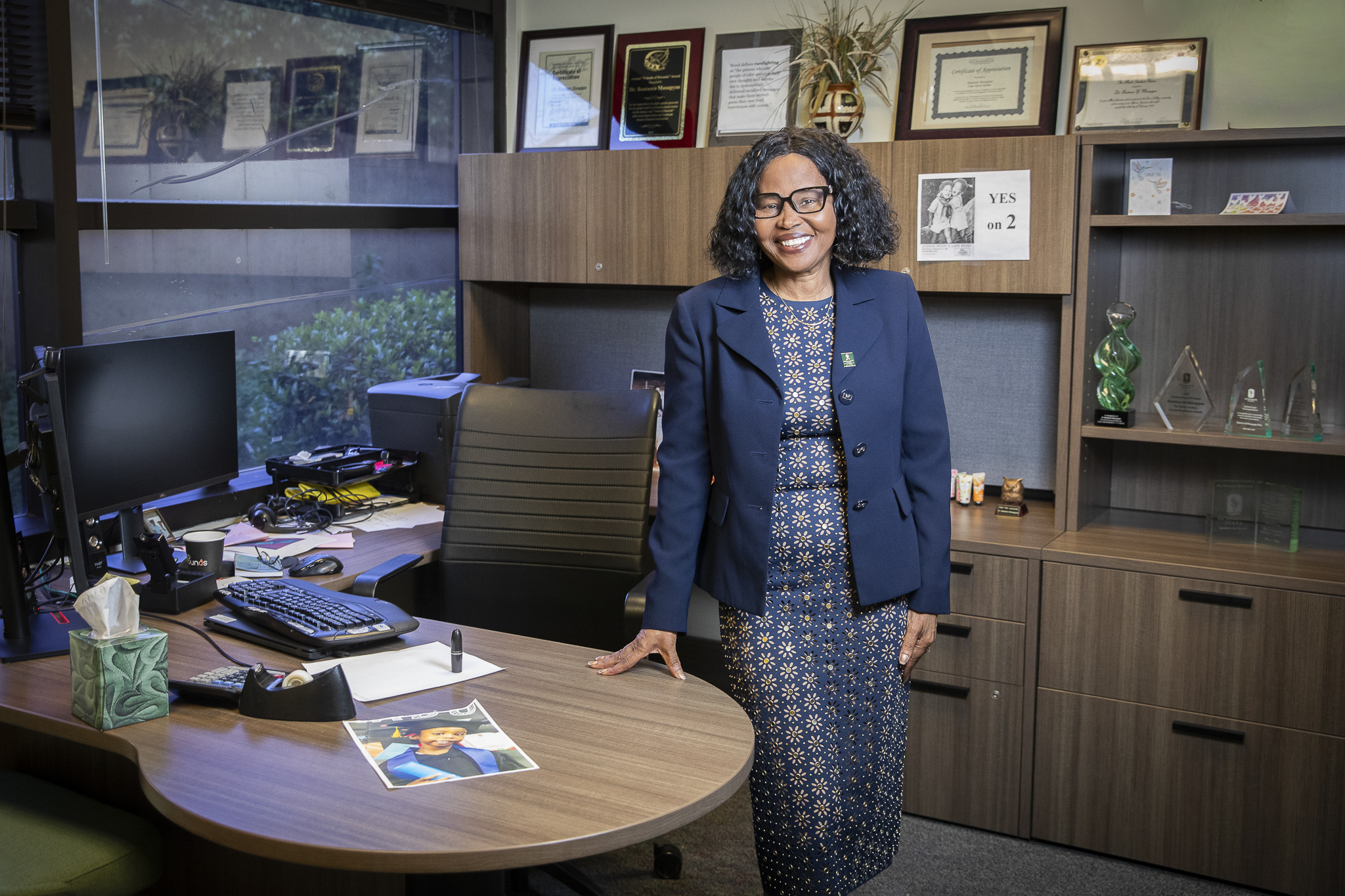 A woman standing by a desk smiles