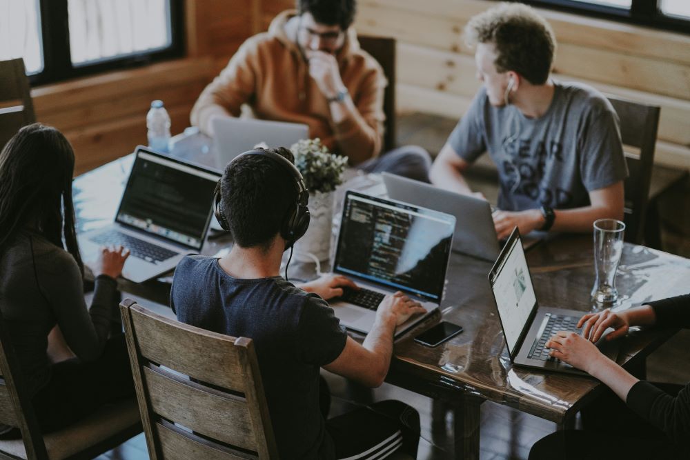 Group of people working independently on laptops at a table