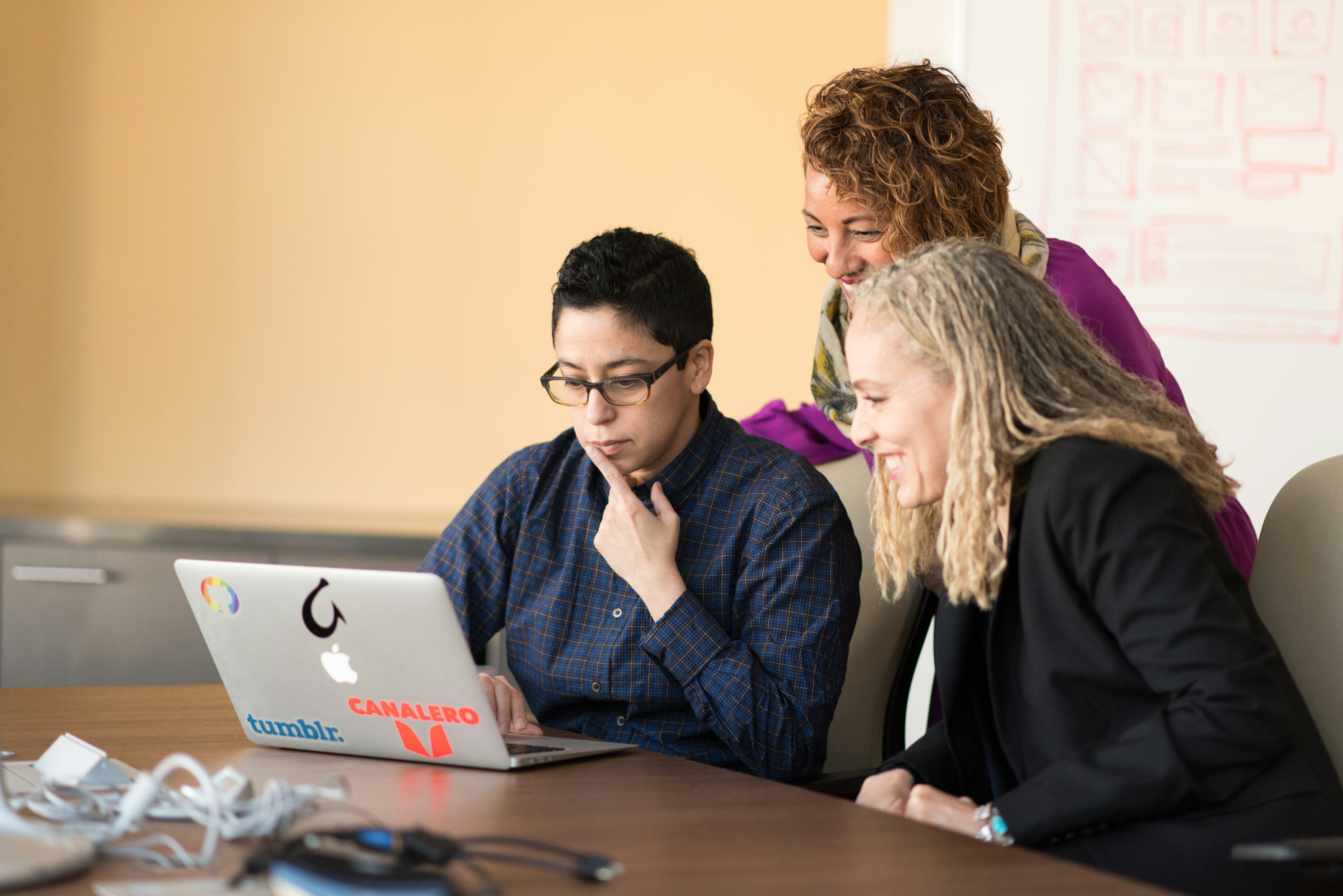 Group of three people working together on a laptop