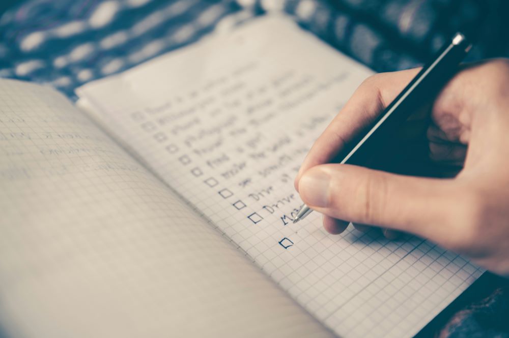 Person writing checklist in a notebook