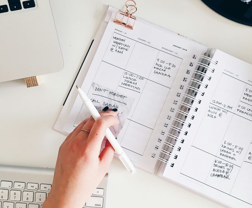 Person scheduling appointments in a planner at an office desk