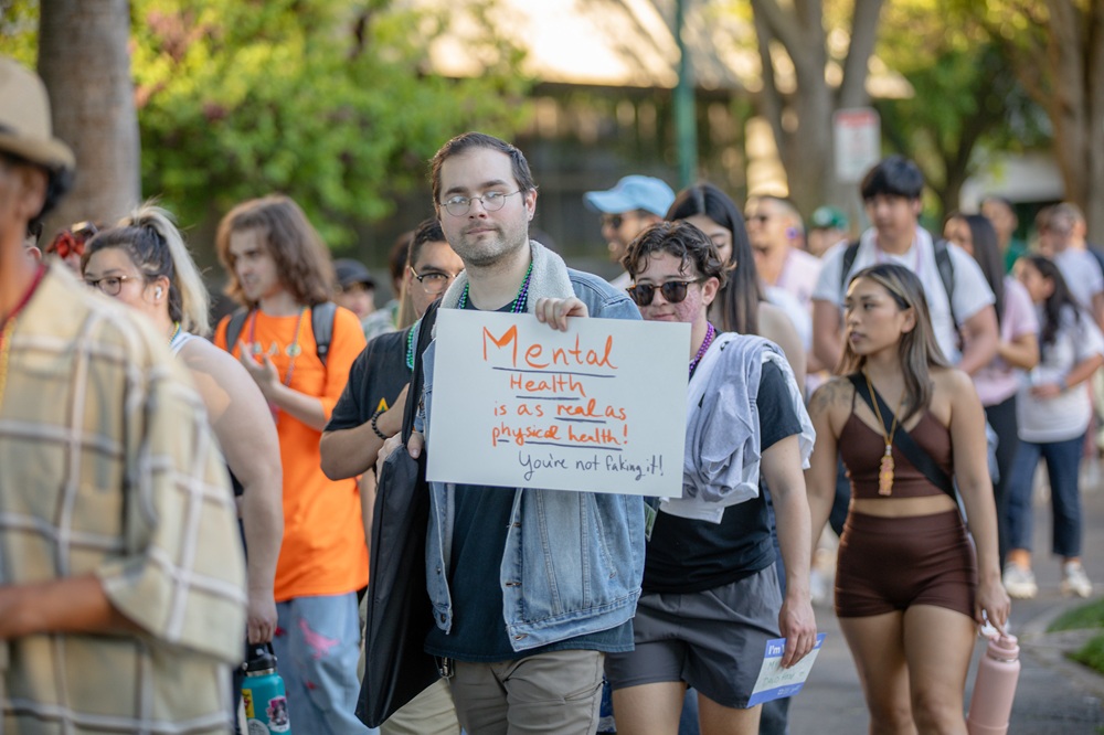 person walking with sign about mental health awareness