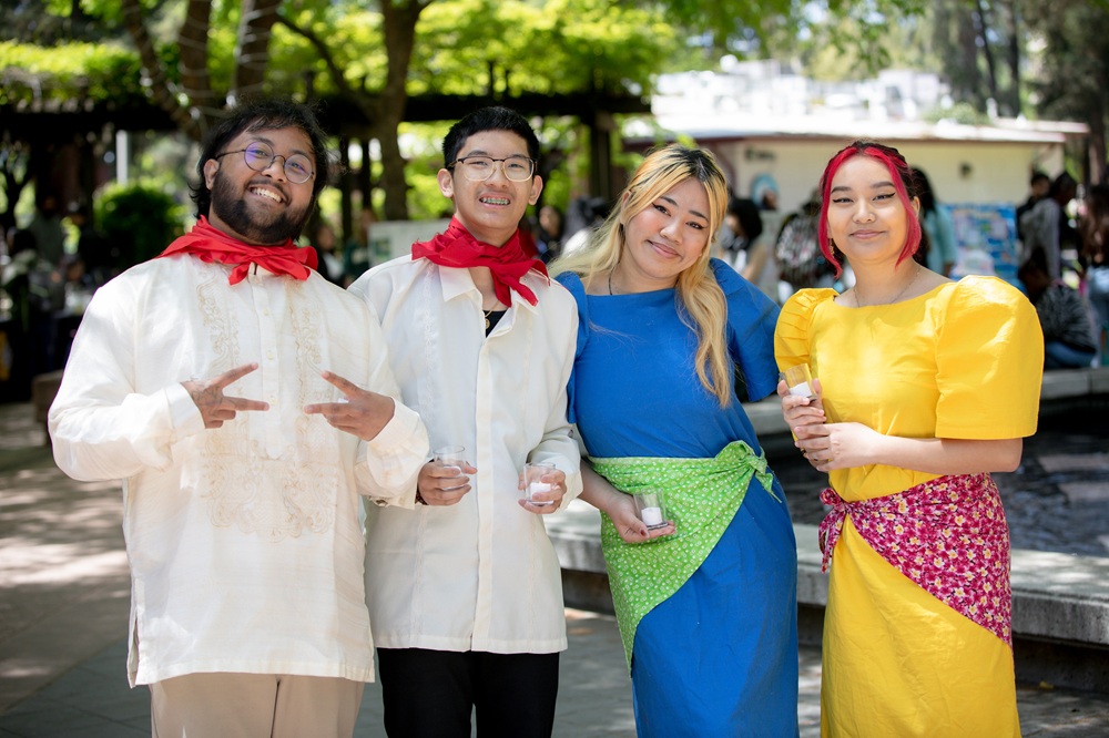 four students smiling and posing for photo on campus