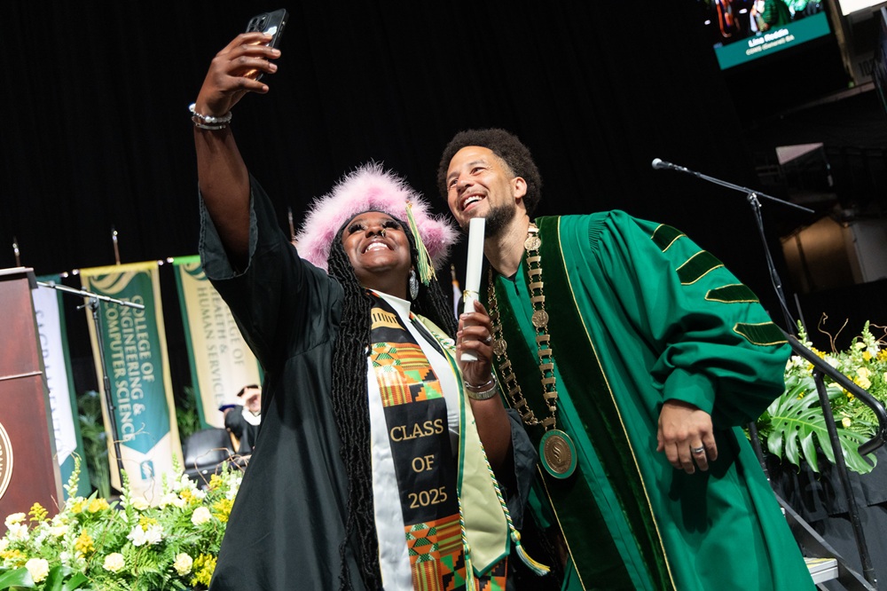 President Wood posing for a selfie with student at commencement ceremony