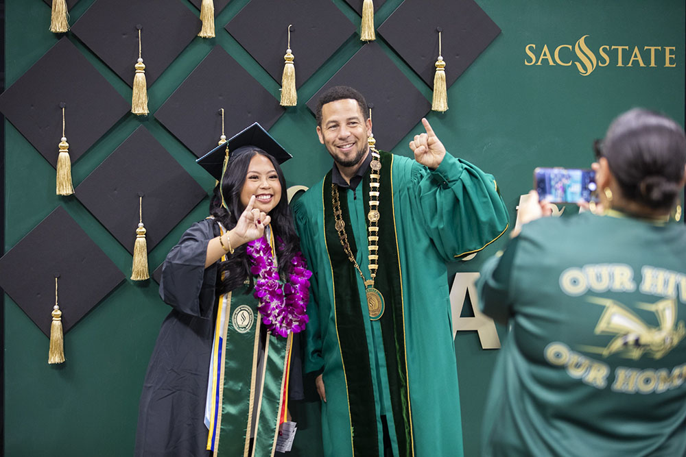 President Wood and a student smiling at the camera during graduation