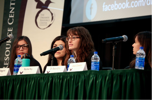 Panelists sitting in front of a table with microphones