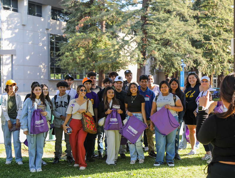 A group of students smiling at the camera standing outdoors.