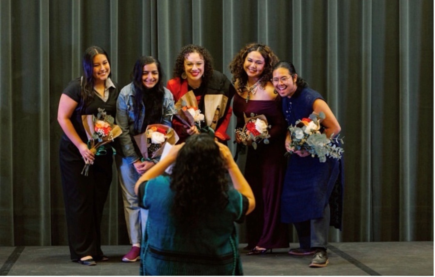 A group of female students with flowers smiling at the camera