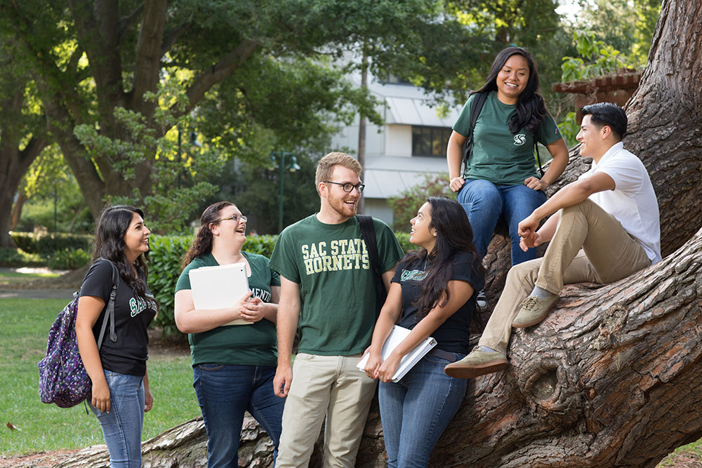 A group of students laughing and looking at each other on campus