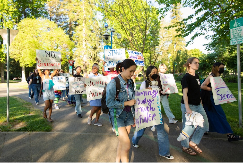 Female students walking with posters in hand.