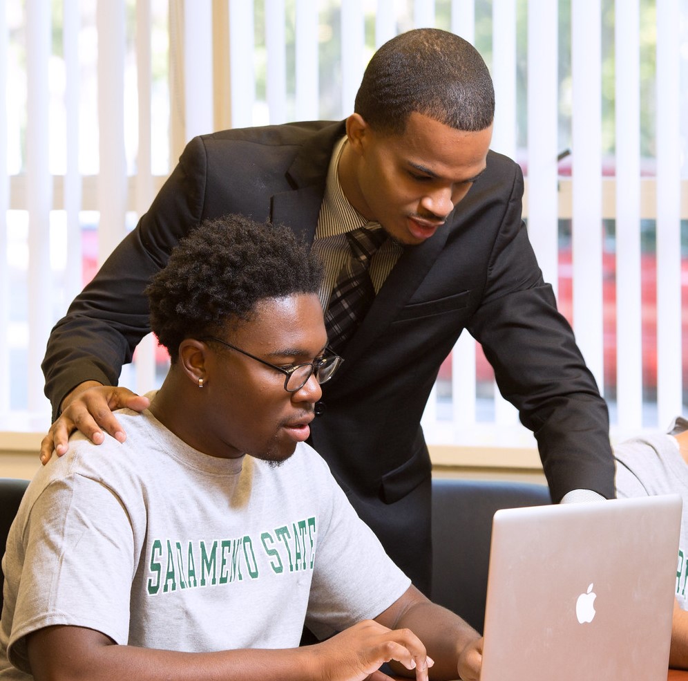 A young male student with his peer mentor working at a laptop
